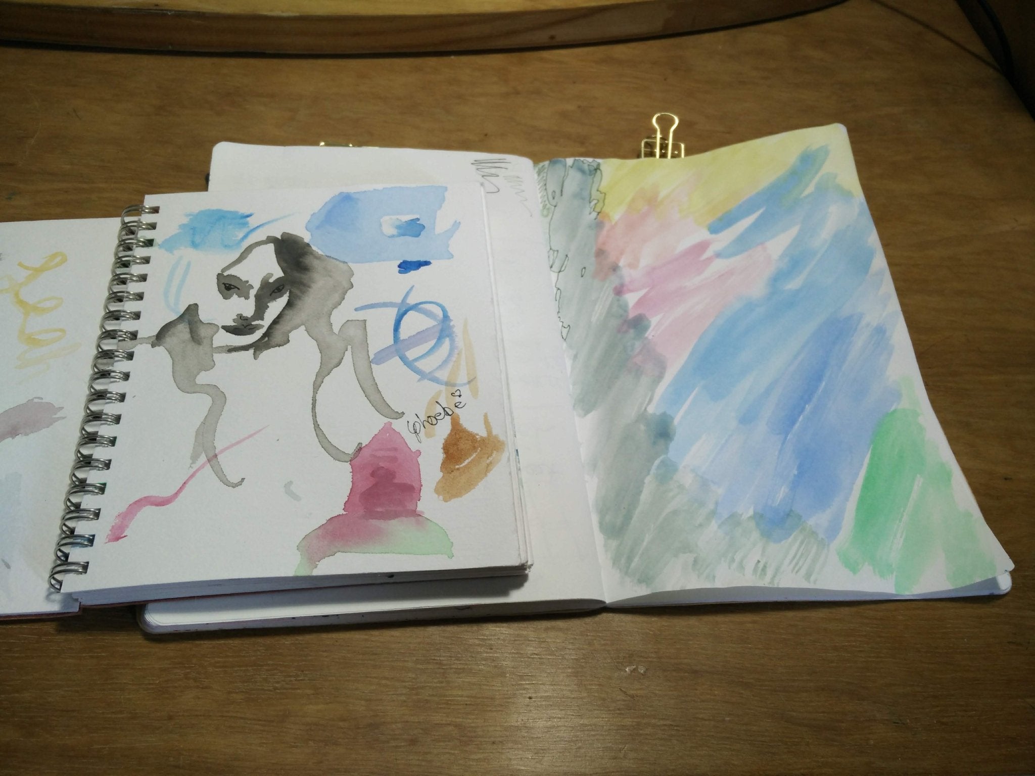 Open sketchbook with artistic drawings on a wooden surface