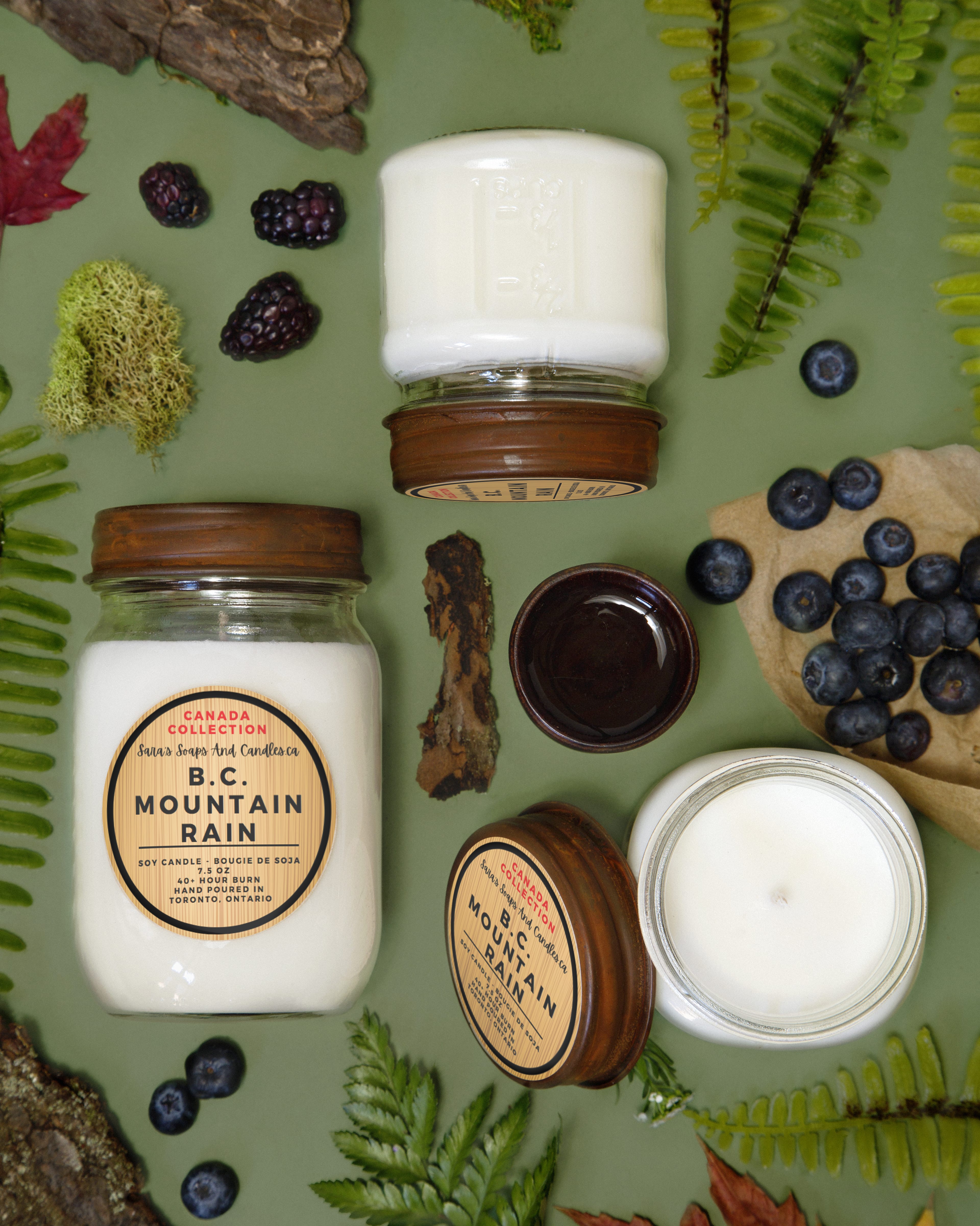 Candles with 'Mountain Rain' label surrounded by nature-themed elements on a green background