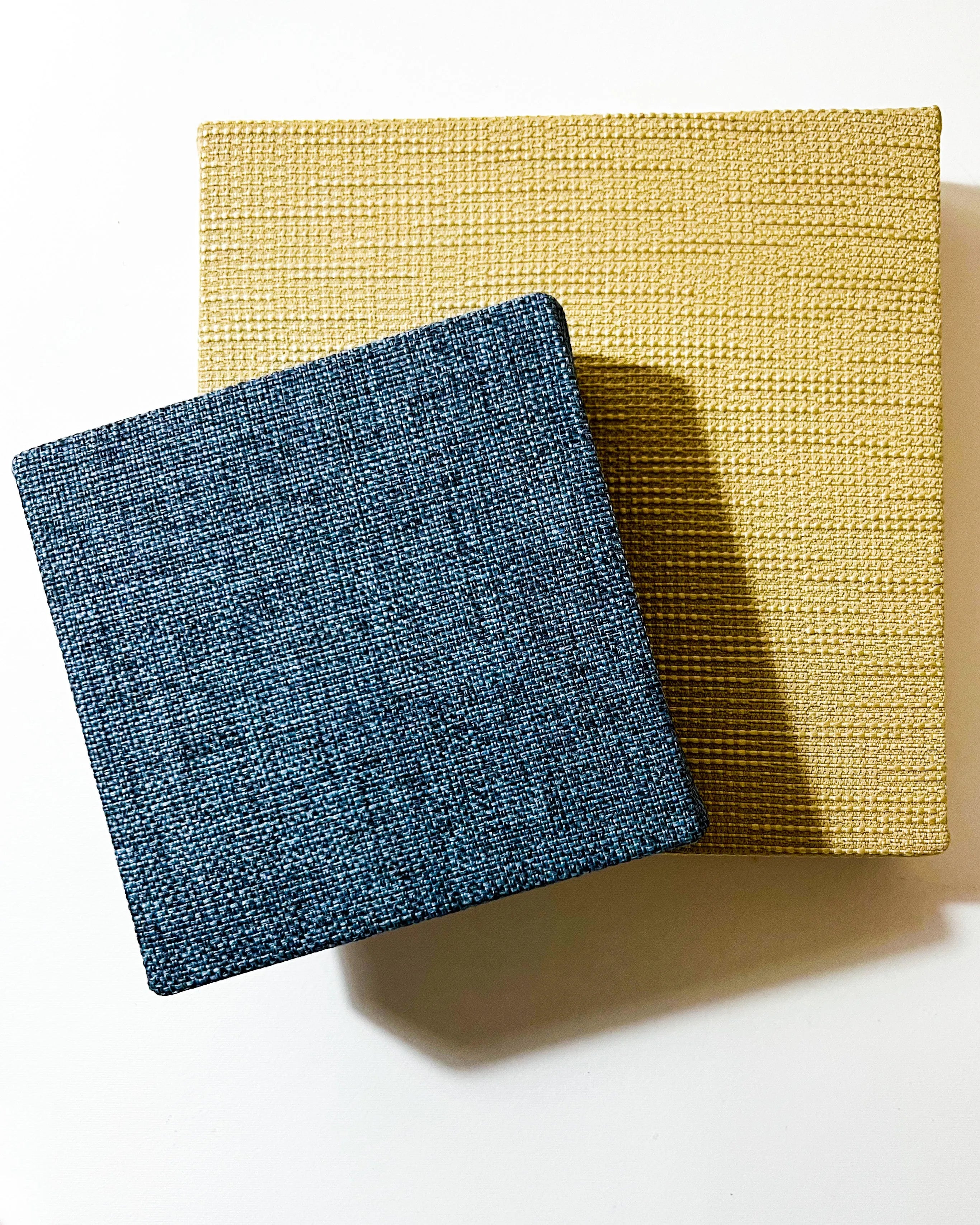 Two square textured tiles, one blue and one yellow, on a white background.
