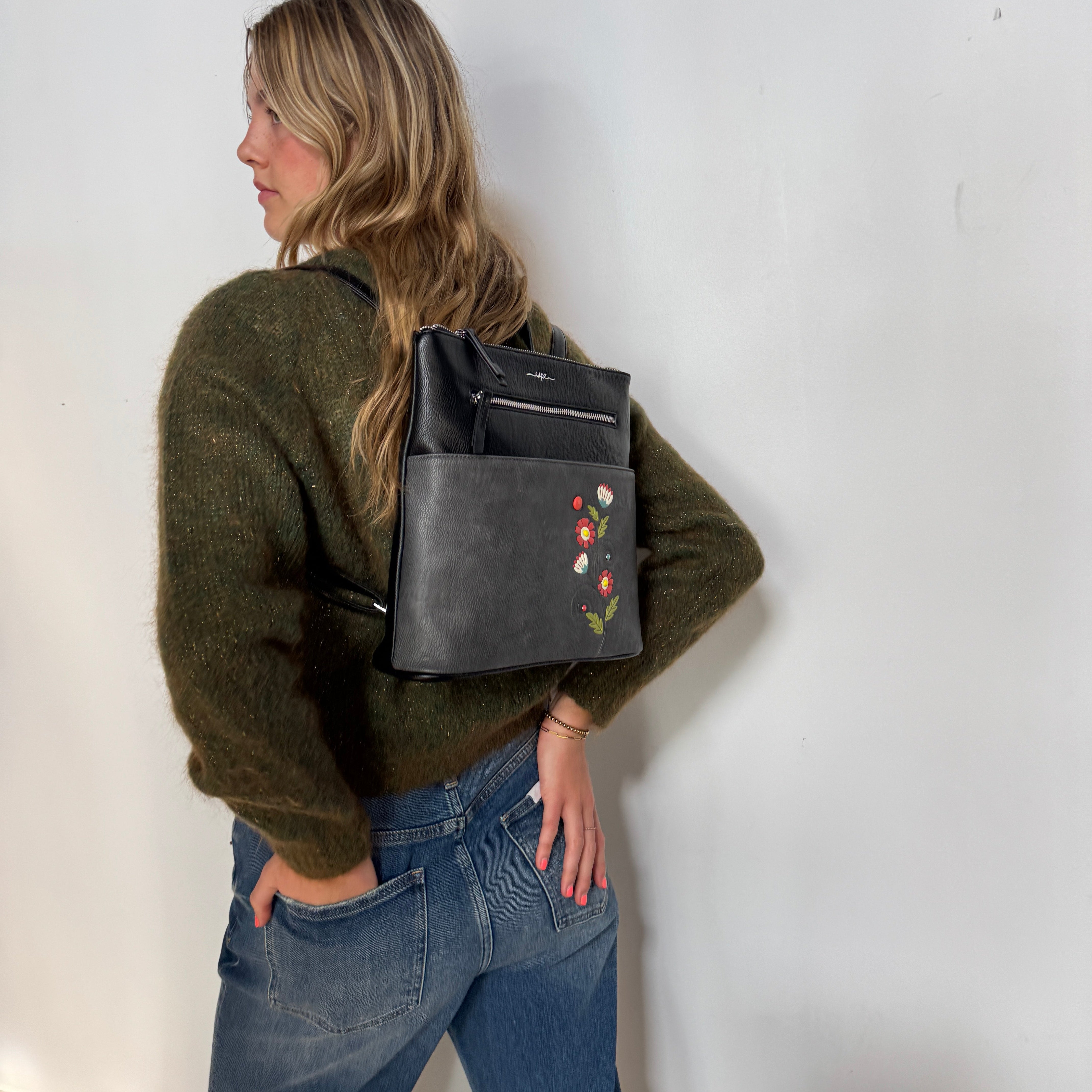 Person wearing a Espe Vegan Corp black backpack featuring colorful designs.