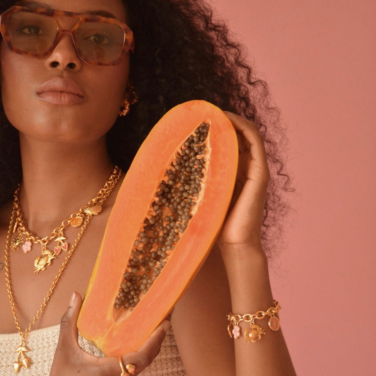 Woman holding a halved papaya with Tropical Vibes Bracelet With Charms by Pinky Mimosa