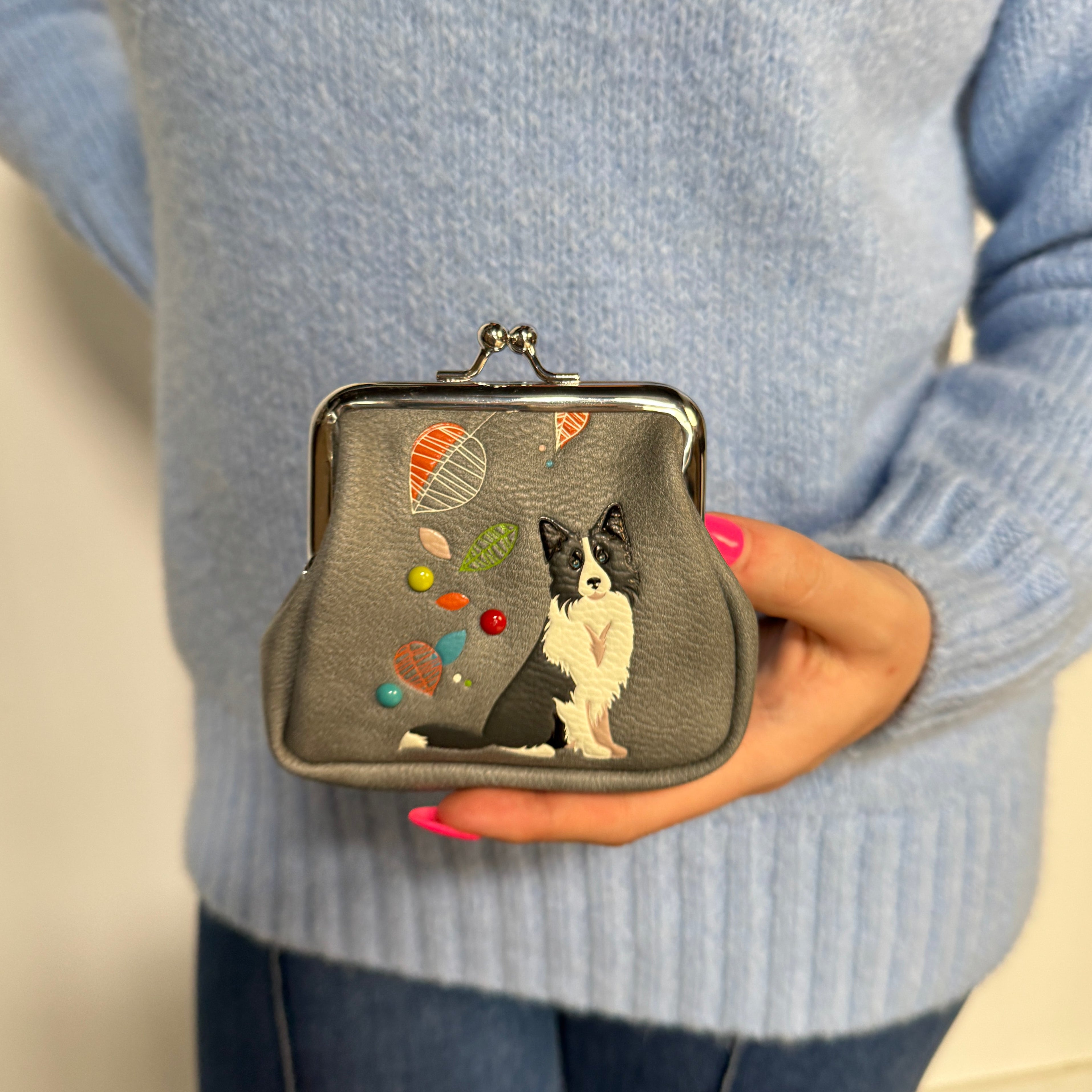 Espe Vegan Corp small kiss-lock coin purse. The purse is grey with an embroidered black and white dog and colorful hot air balloon motifs, held against a simple indoor background.