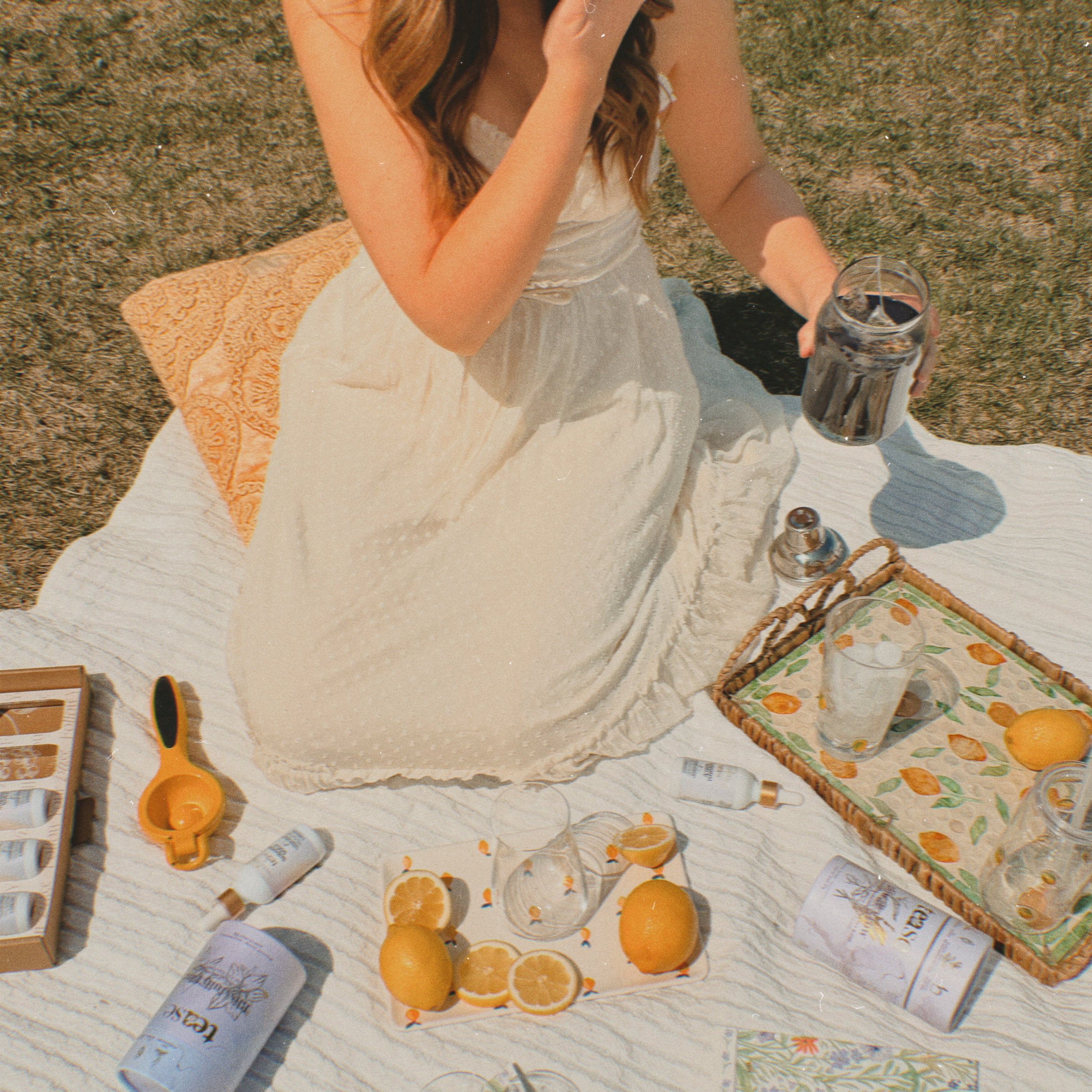 Ananda Elixirs Shroom Soda® – Lavender Lemonade – Woman at outdoor picnic holding blue Shroom Soda mocktail with lemons and Tease tea