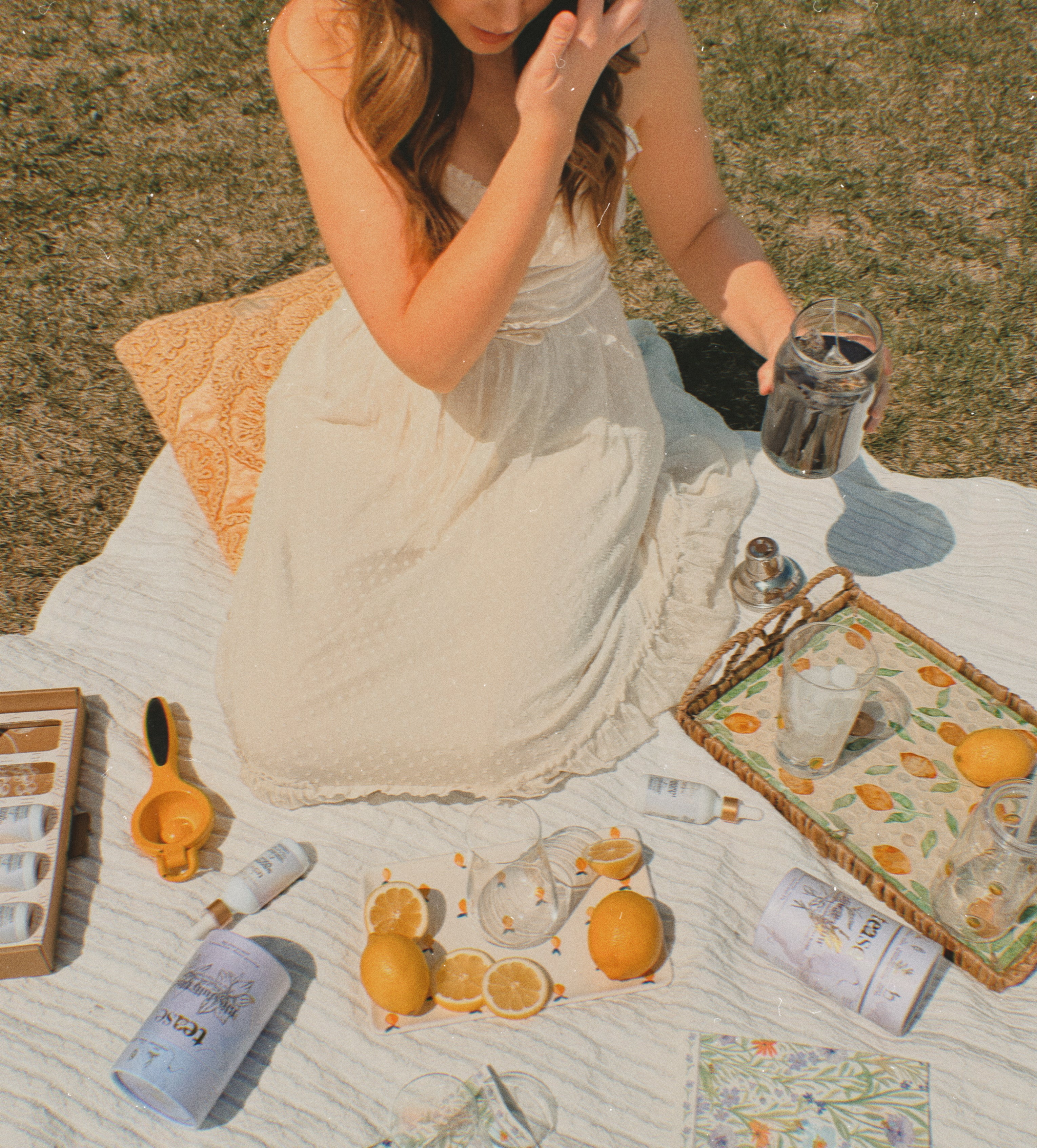 Ananda Elixirs Shroom Soda® – Lavender Lemonade – Woman at outdoor picnic holding blue Shroom Soda mocktail with lemons and Tease tea