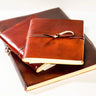 Stack of leather-bound books with a gold ribbon on a white background