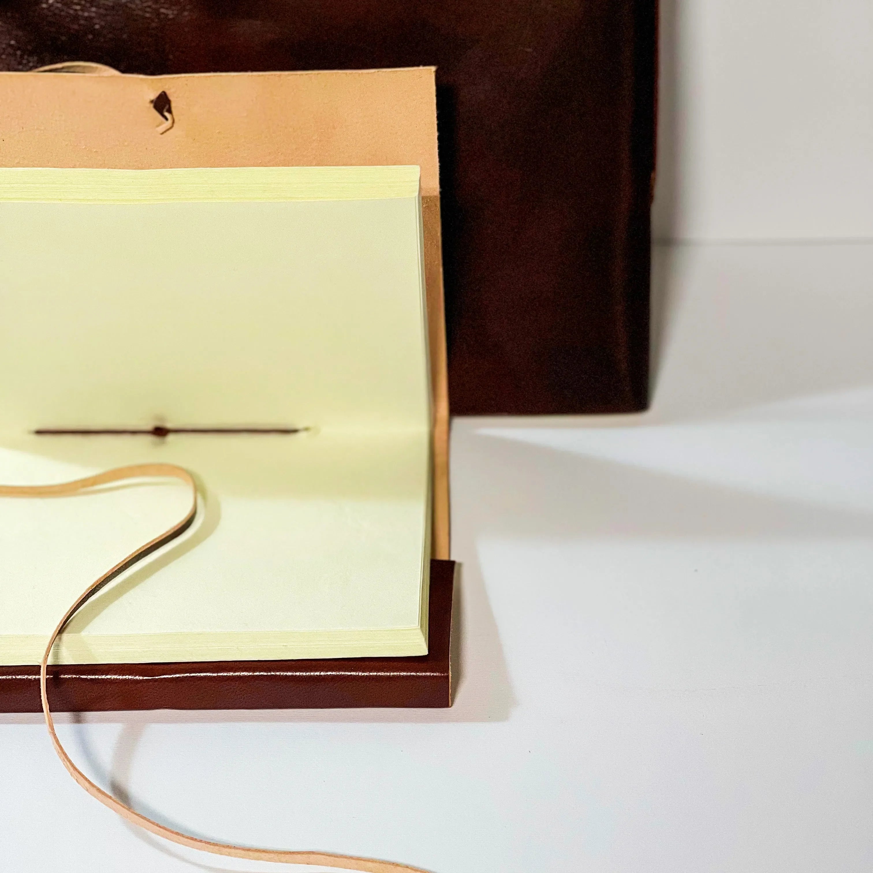 Open brown leather-bound book with a yellow interior on a white surface.