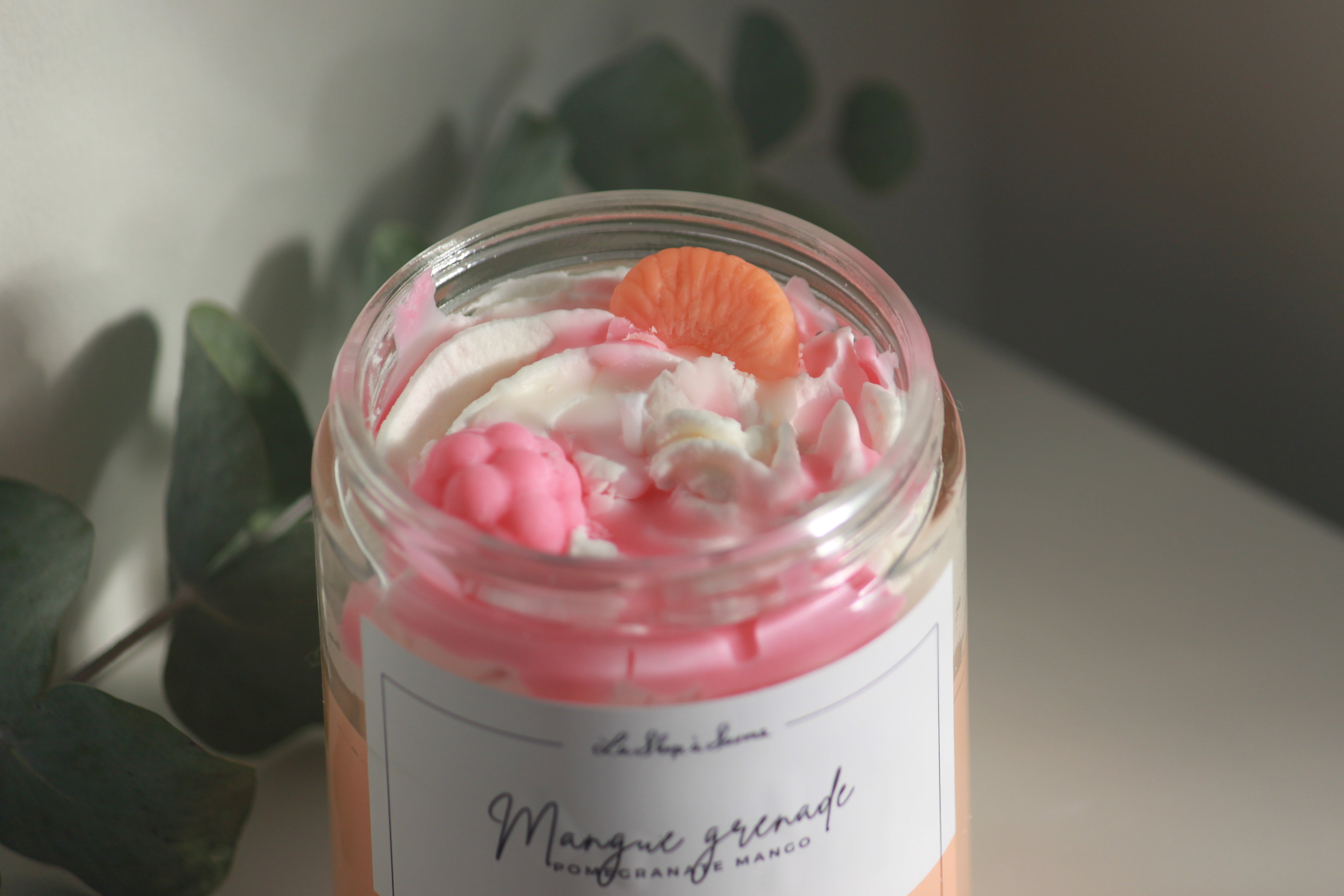 Jar of pink and white whipped cream with a label on a light background