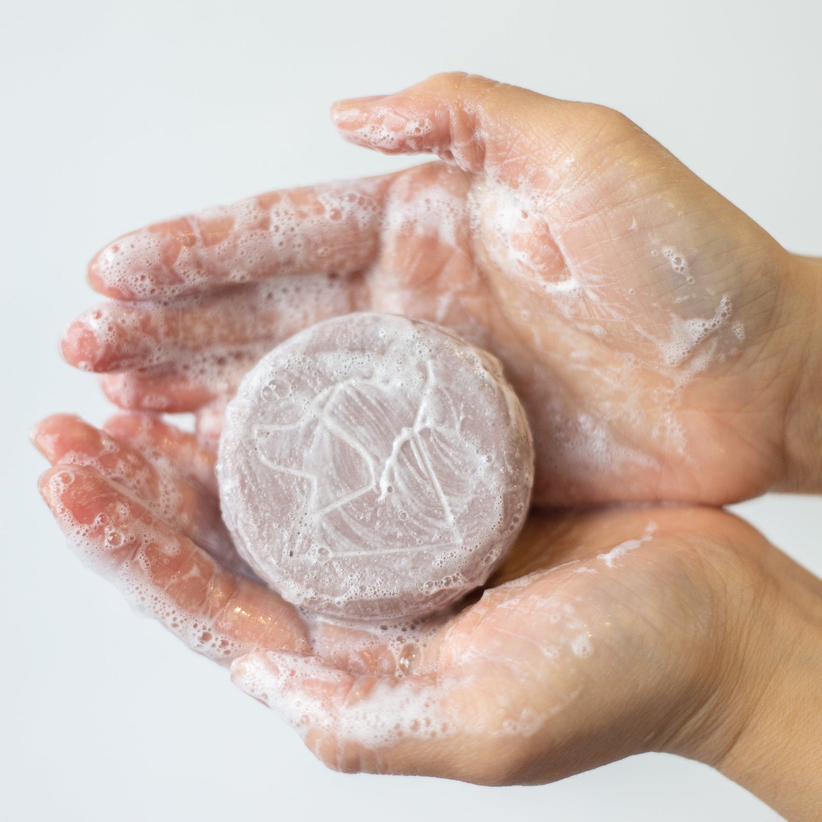 Hand holding a round, white, textured object against a light background