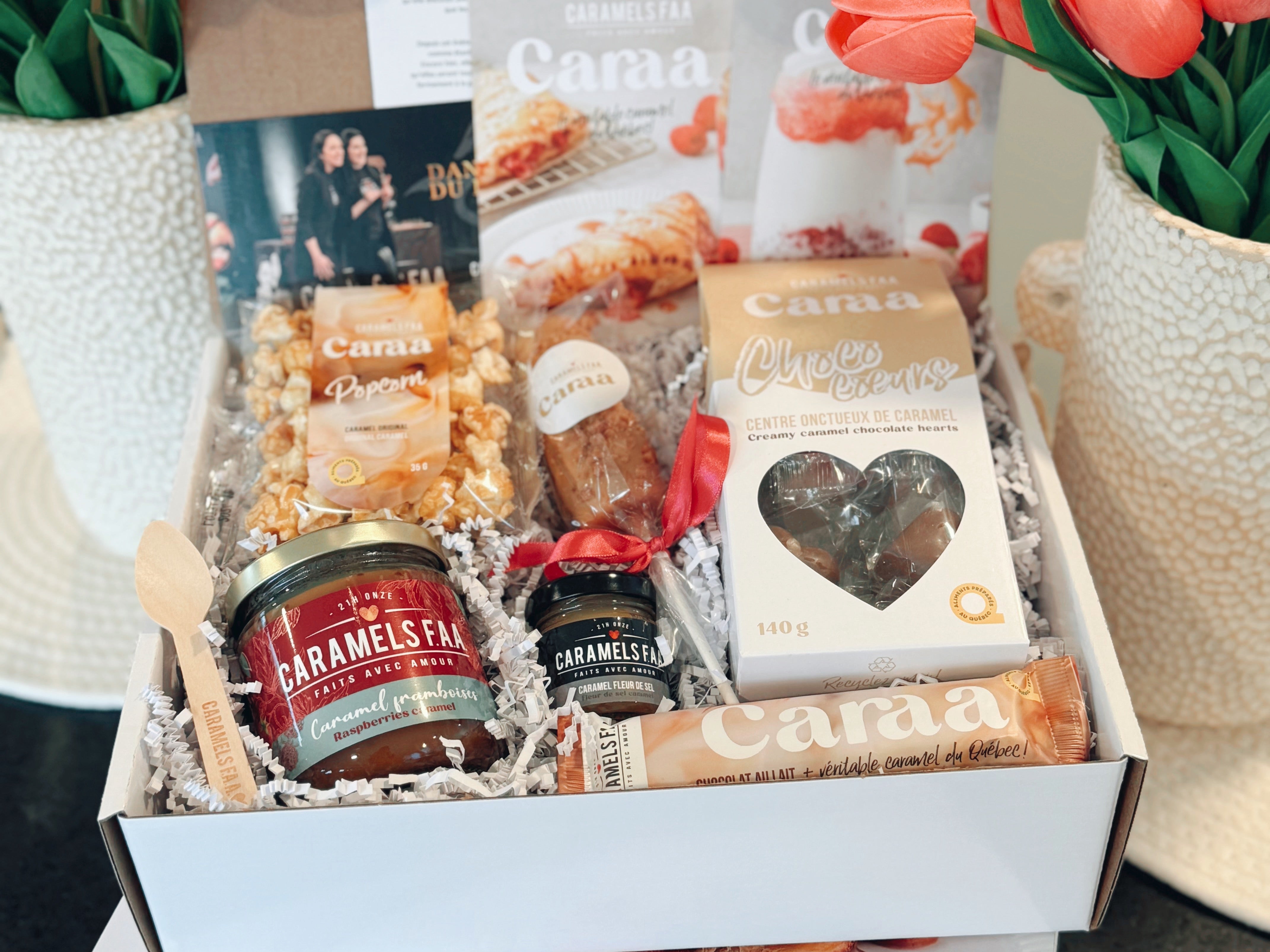 Gourmet gift box with snacks and a card, branded 'Caraa', on a neutral background.