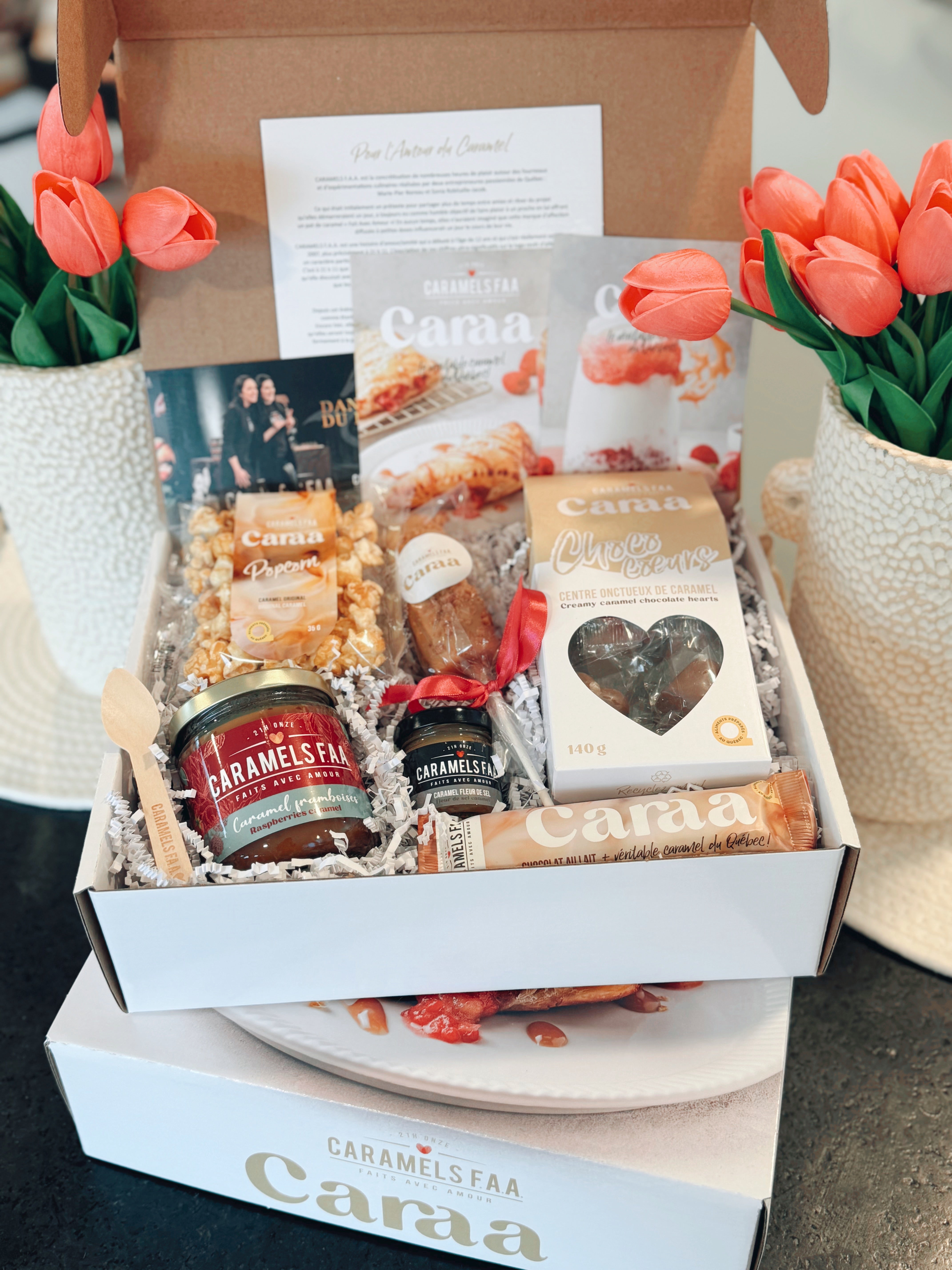 Gourmet gift box with snacks and a card, branded 'Caraa', on a neutral background.