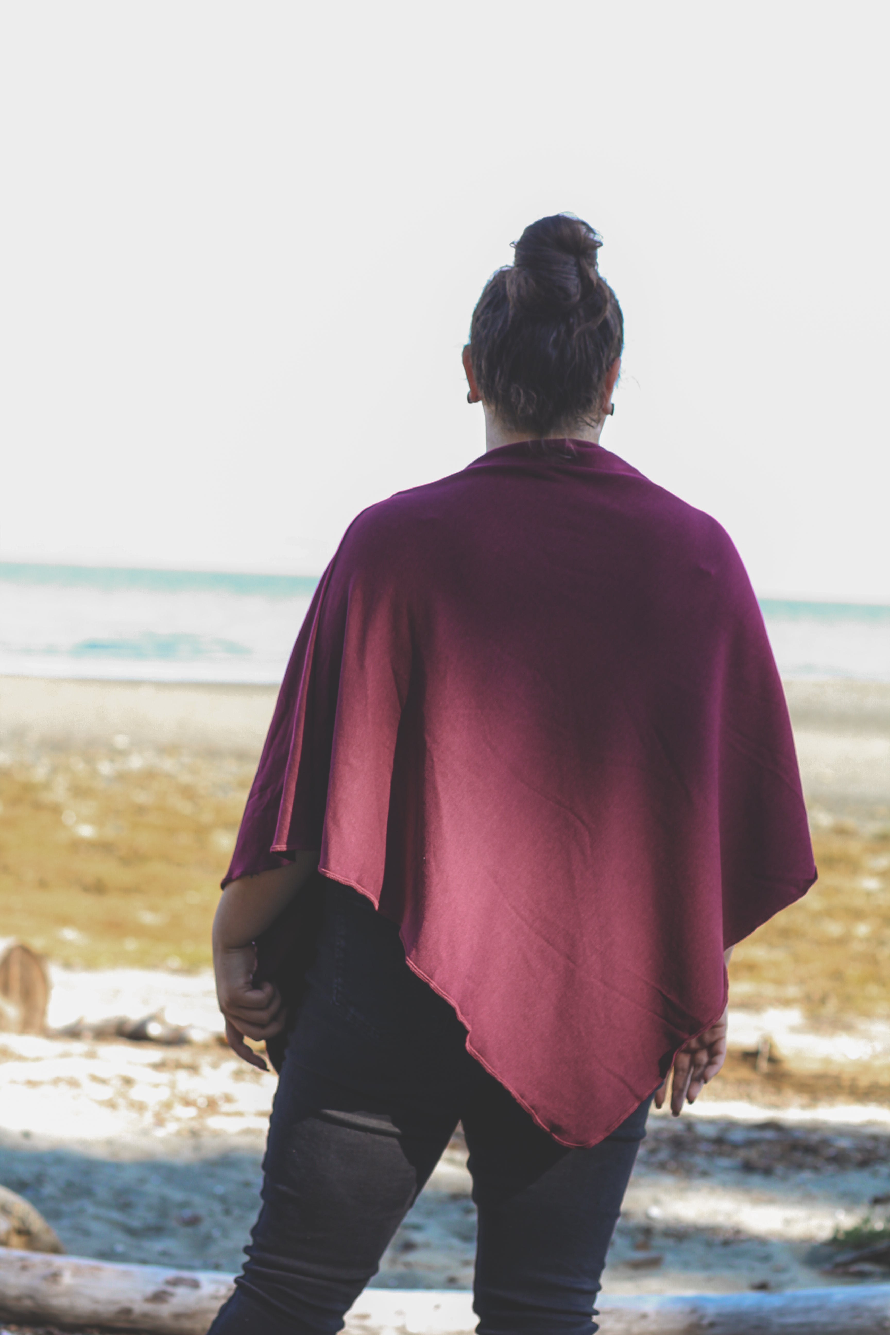 Person wearing a burgundy poncho standing on a beach