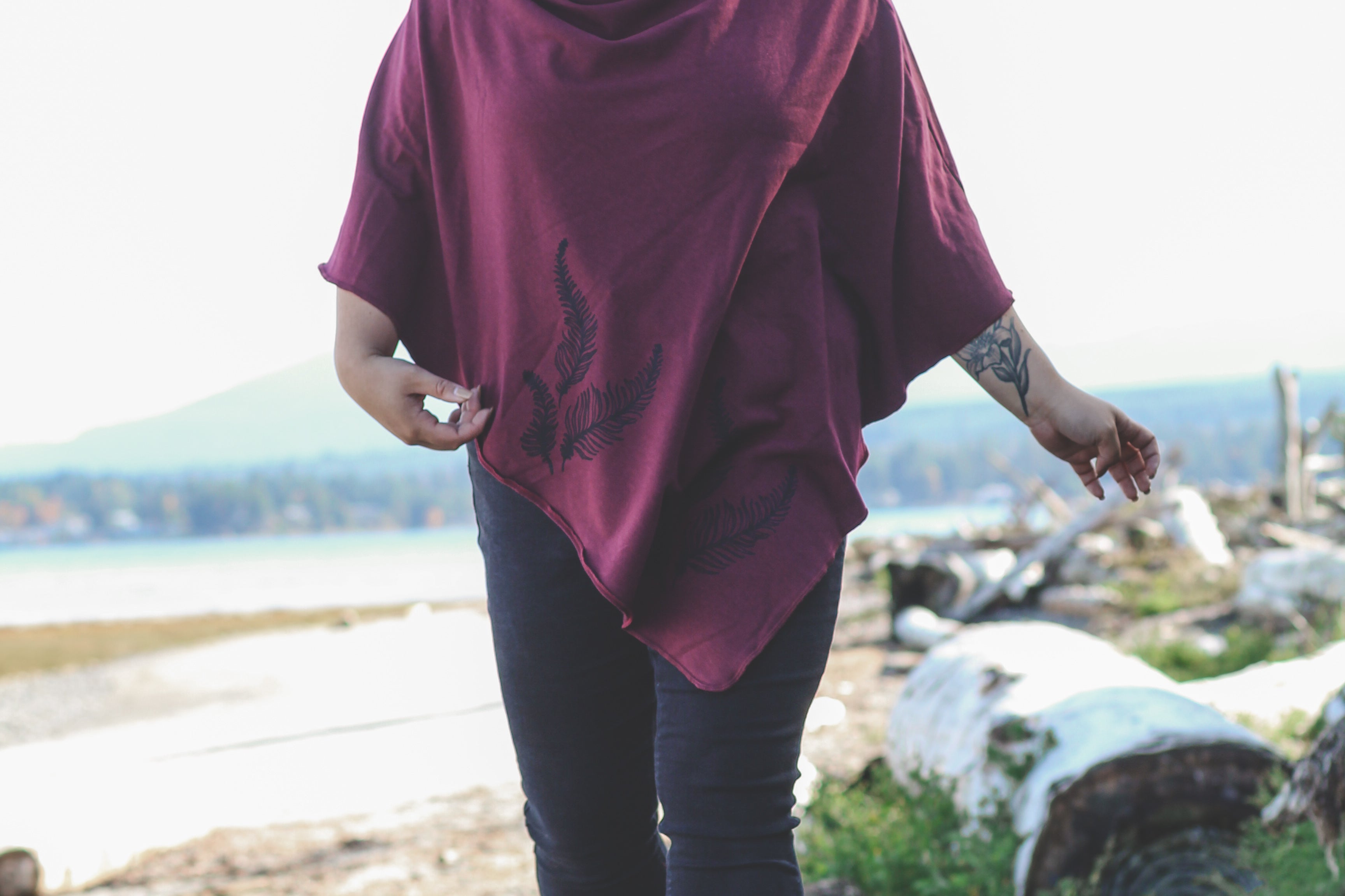 Person wearing a maroon poncho walking on a log in a natural setting
