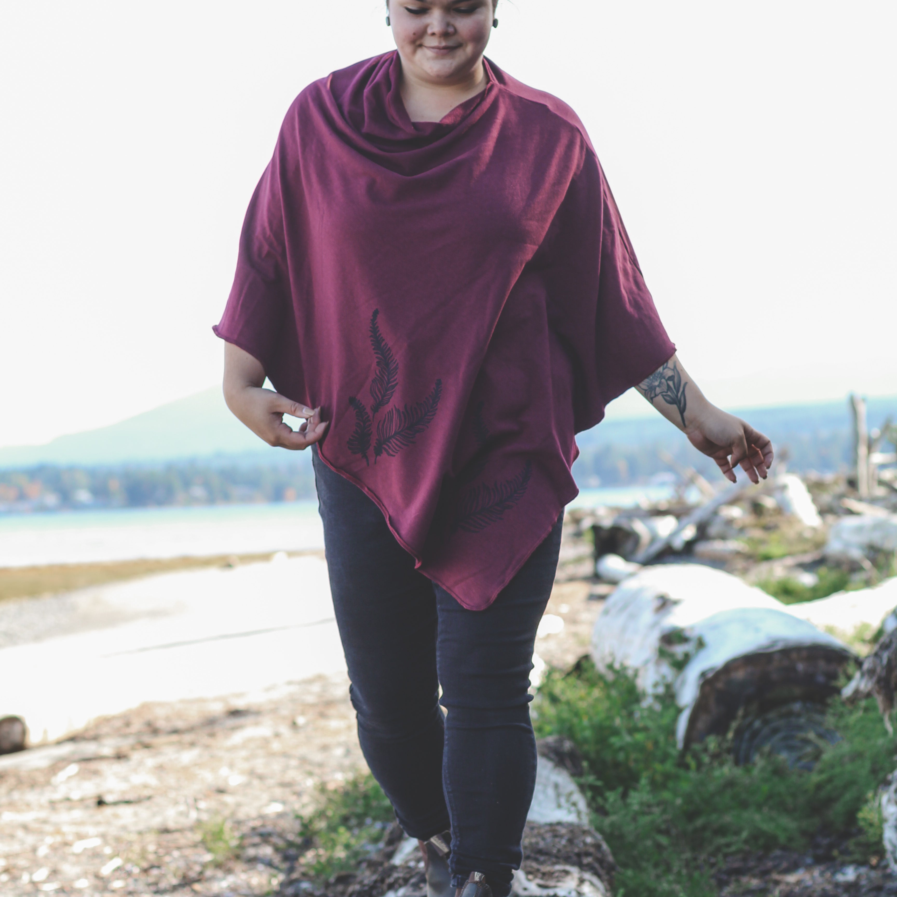 Person wearing a maroon poncho walking on a log in a natural setting