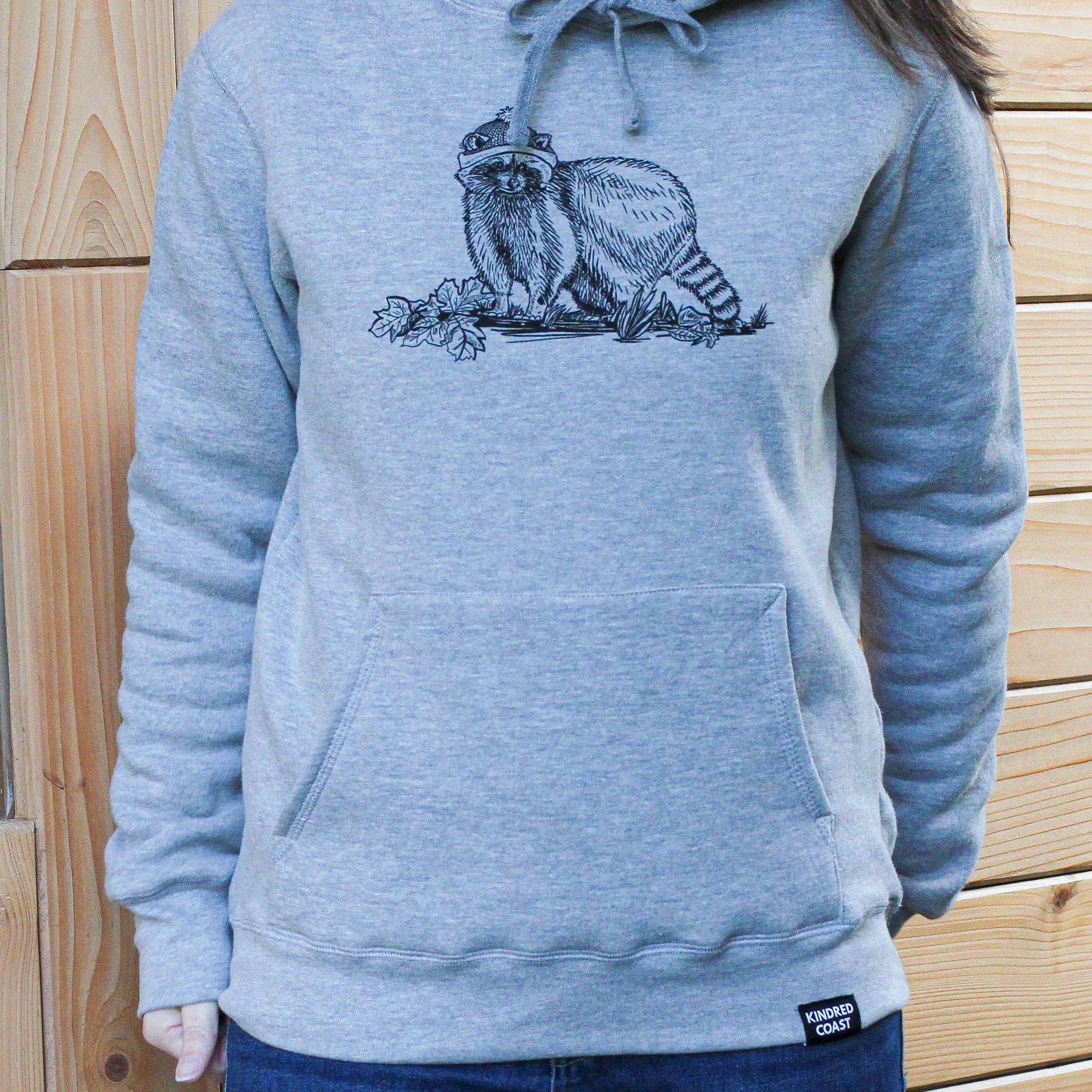 Person wearing a gray hoodie with a graphic design against a wooden background