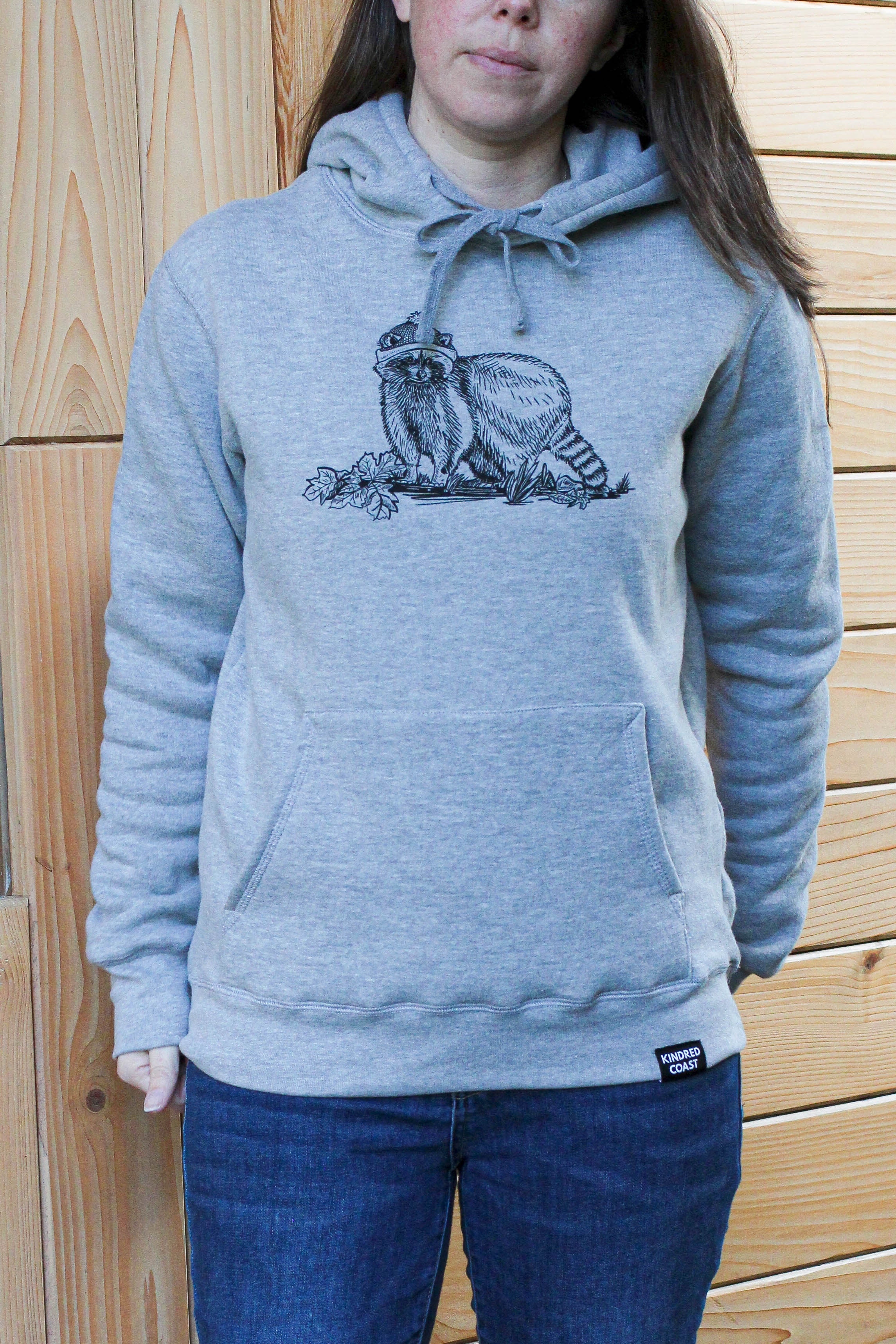 Person wearing a gray hoodie with a graphic design against a wooden background