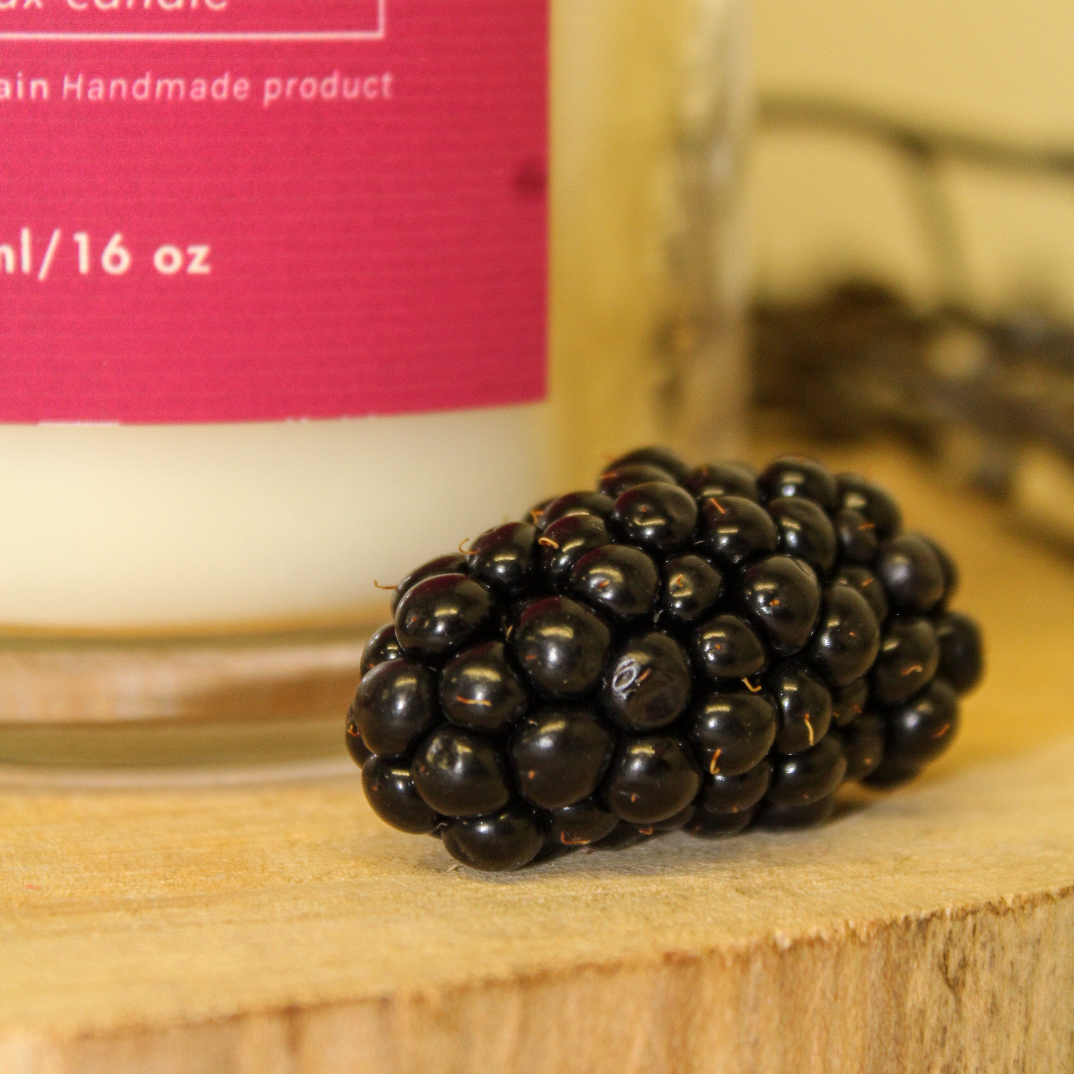 Candle with a blackberry on a wooden surface