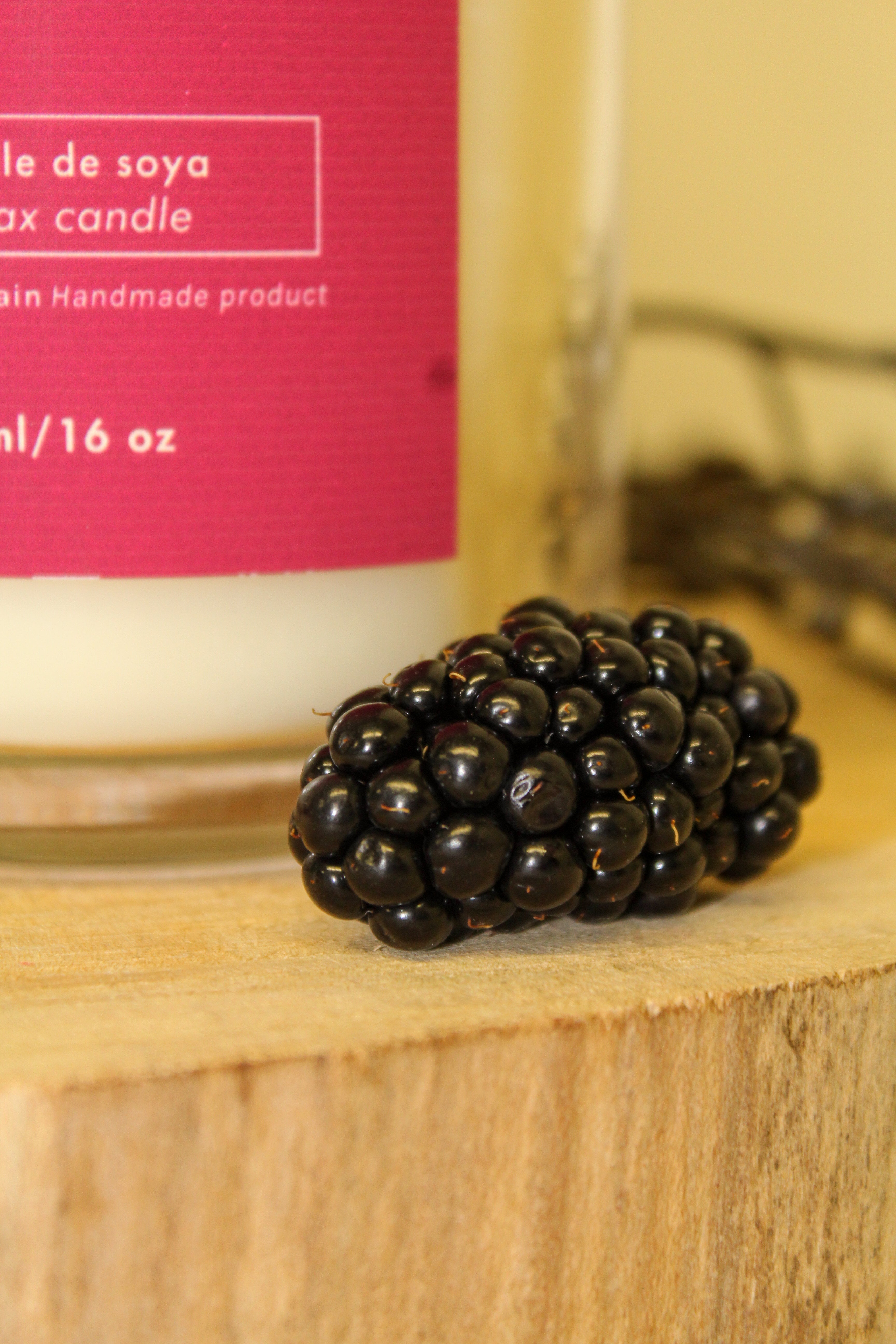 Candle with a blackberry on a wooden surface