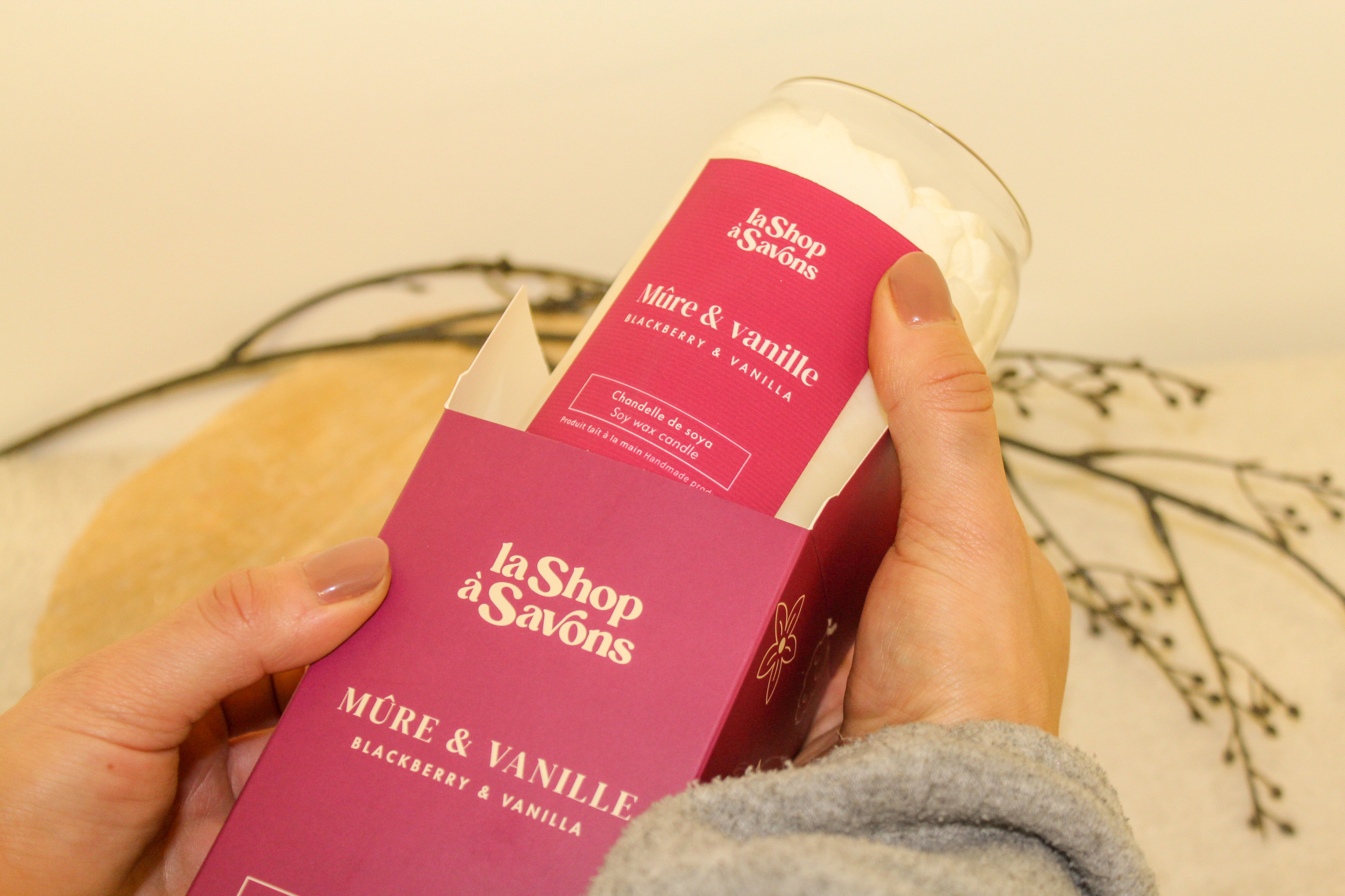 Hand holding a product with 'la Shop à Savons' packaging against a neutral background