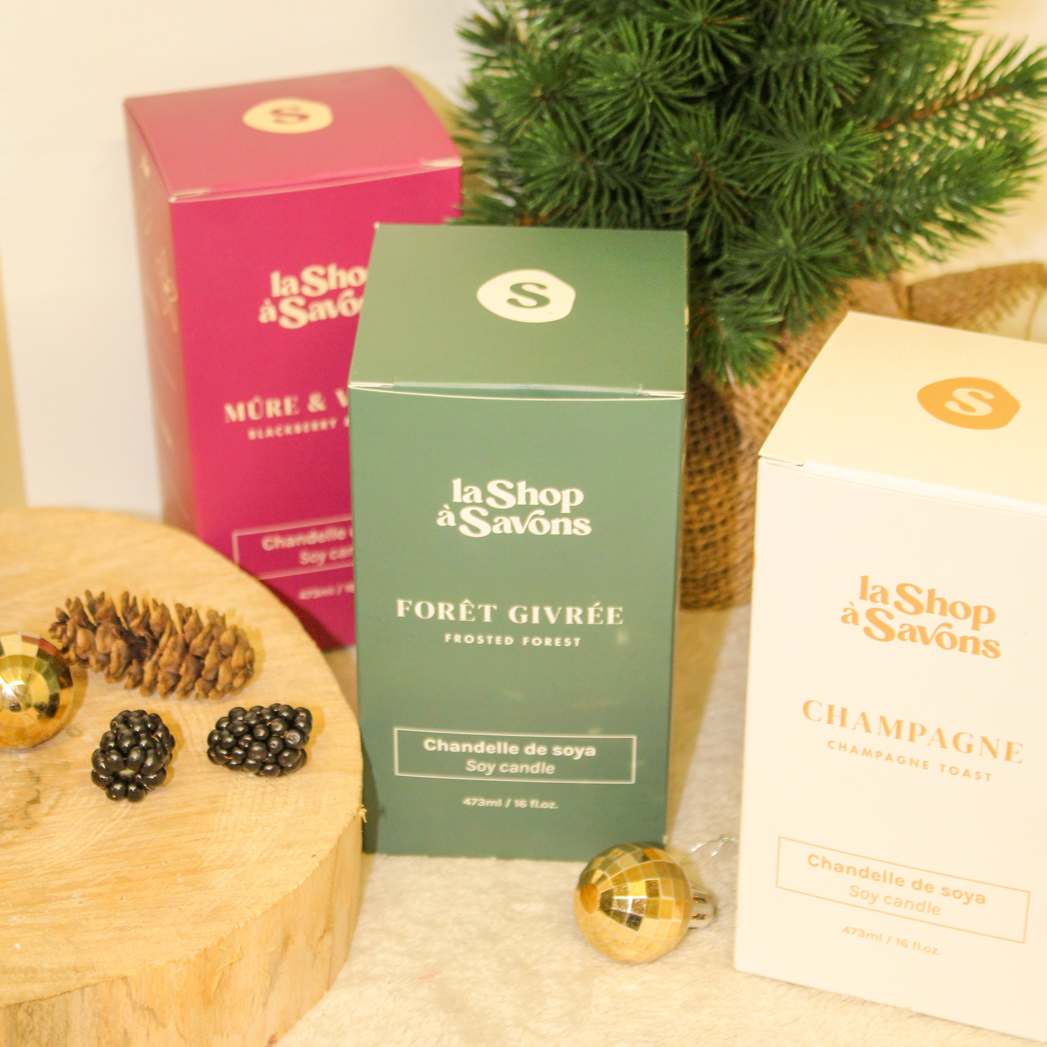 Three boxes of 'La Shop des Savons' with decorative items on a beige surface.