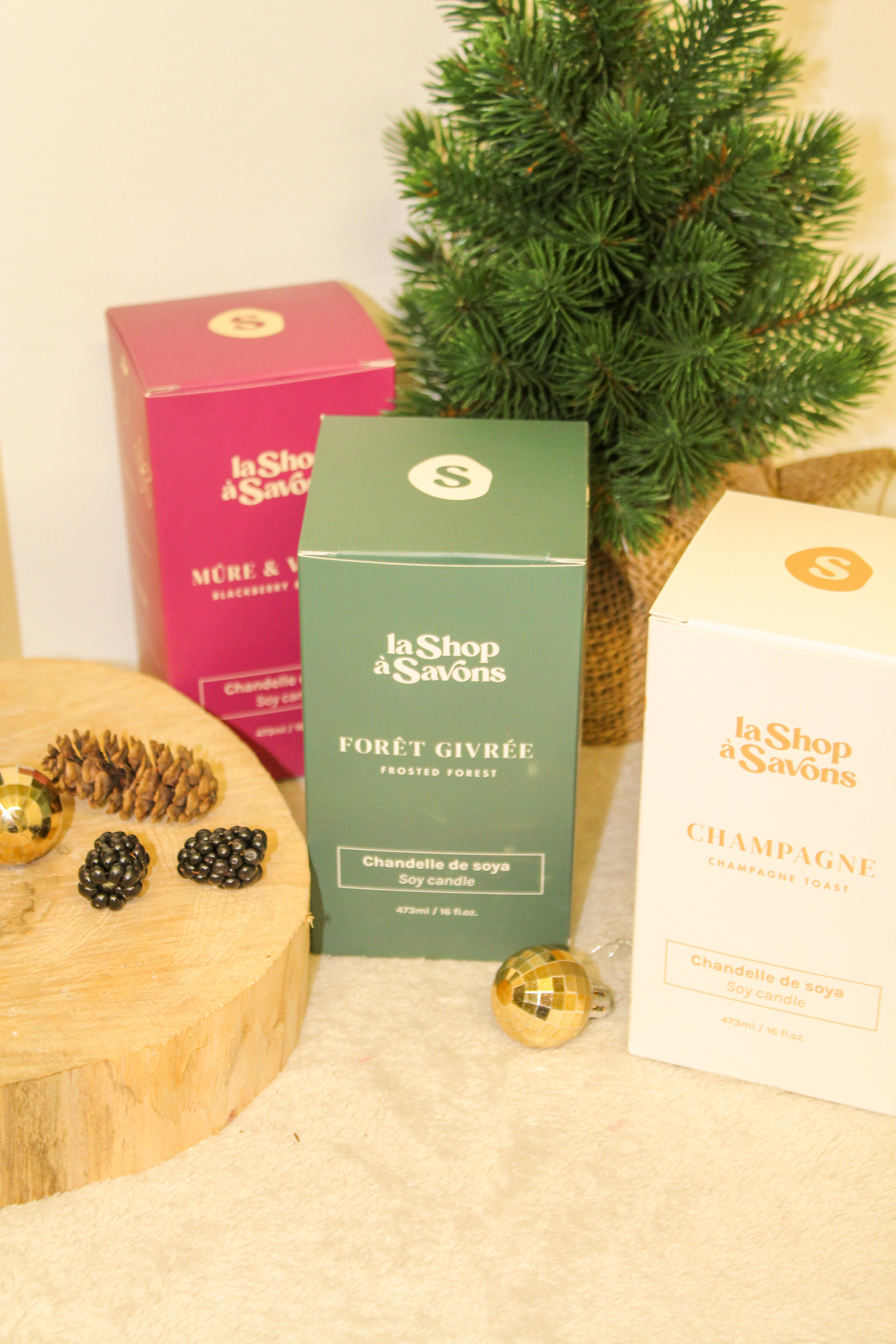 Three boxes of 'La Shop des Savons' with decorative items on a beige surface.
