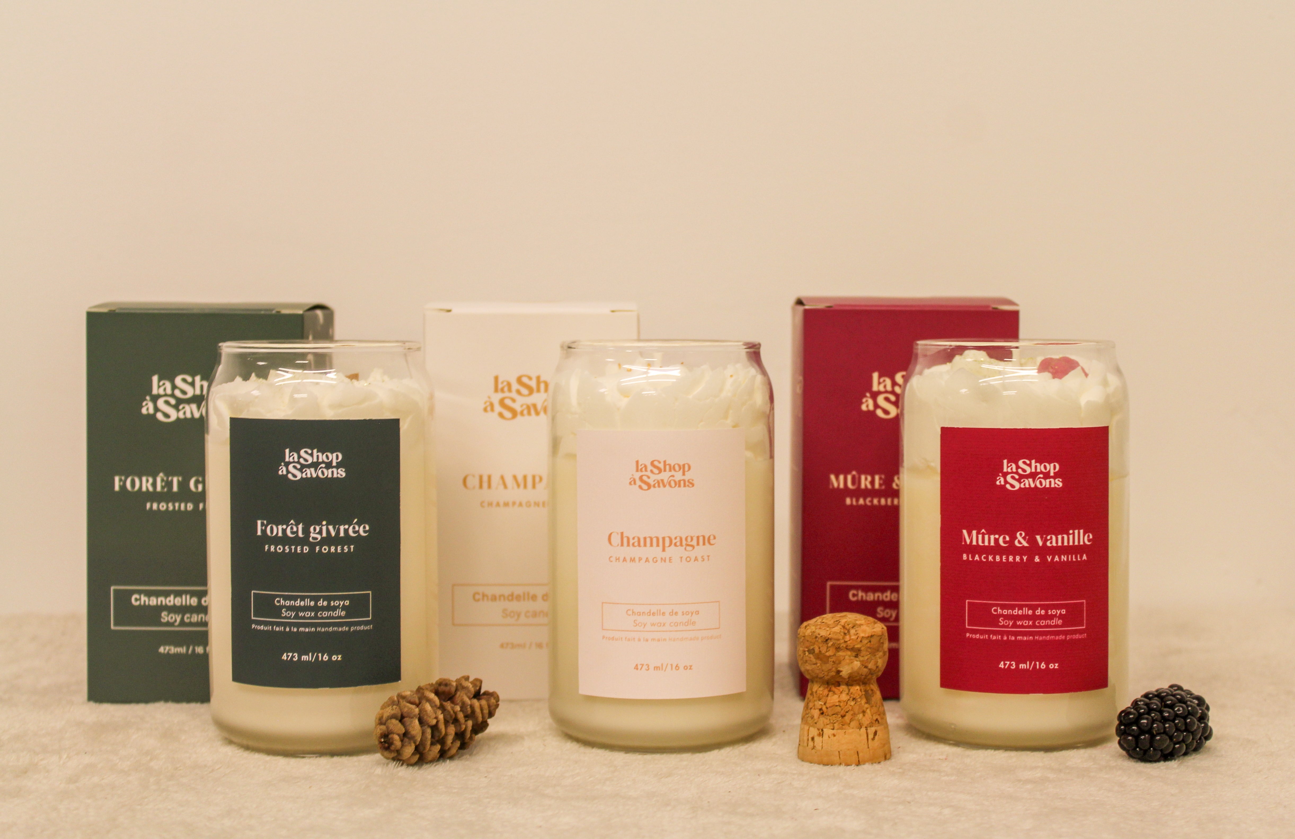 Collection of candles and packaging with visible brand labels on a neutral background