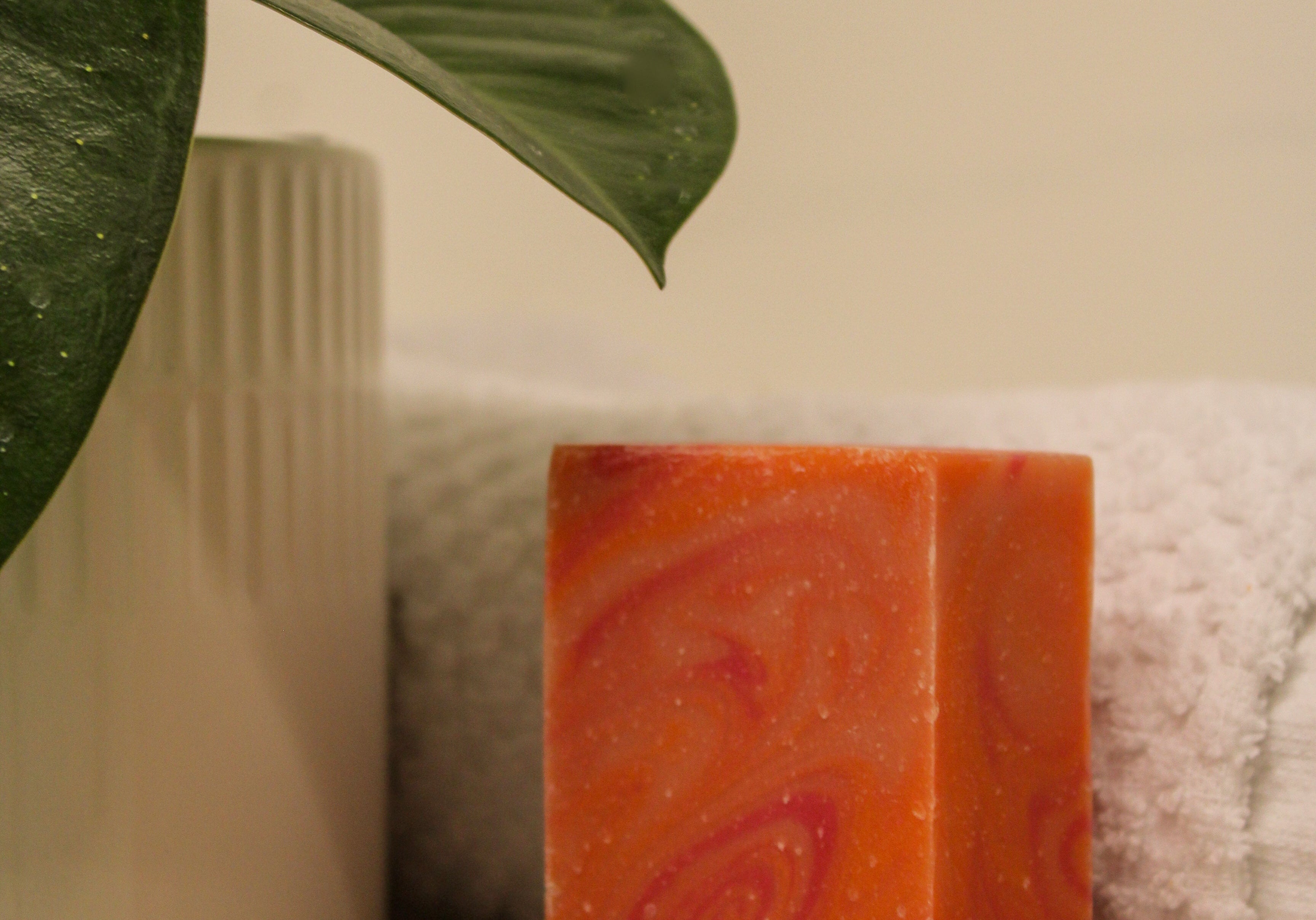 Orange soap bar with a spiral design on a towel next to a plant