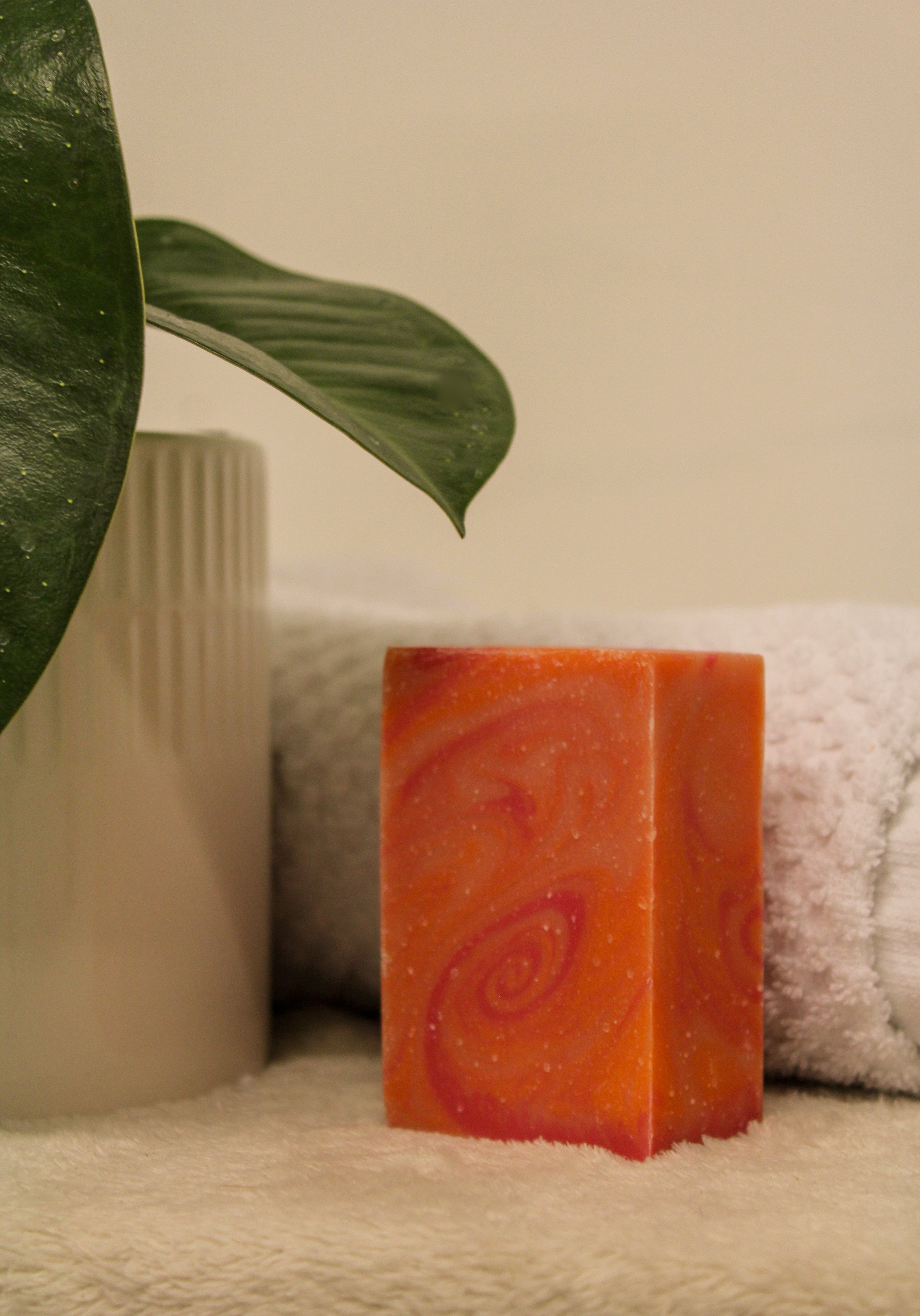 Orange soap bar with a spiral design on a towel next to a plant