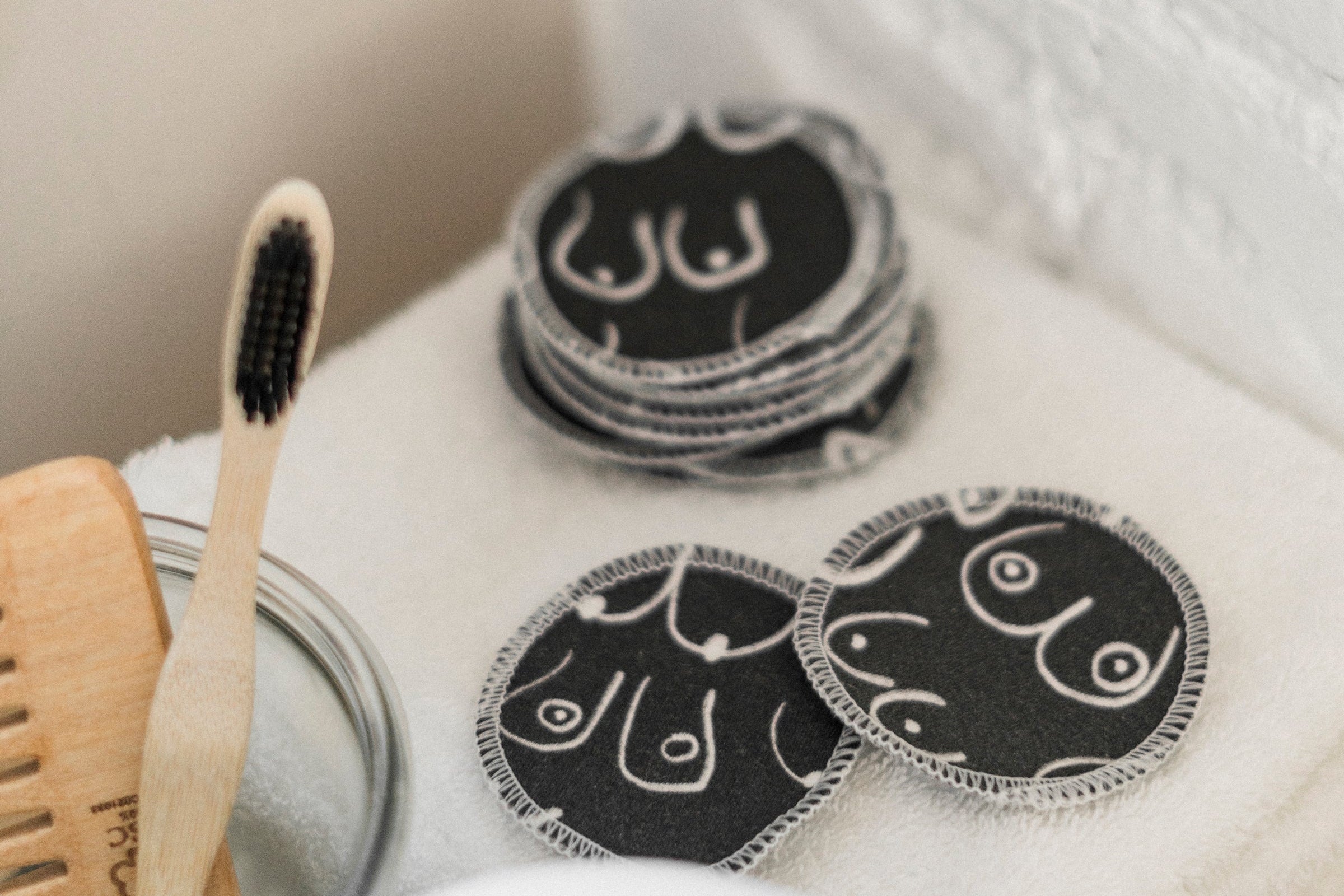 Black and white resuable cotton makeup pads on a white cloth by Freon Collective stacked