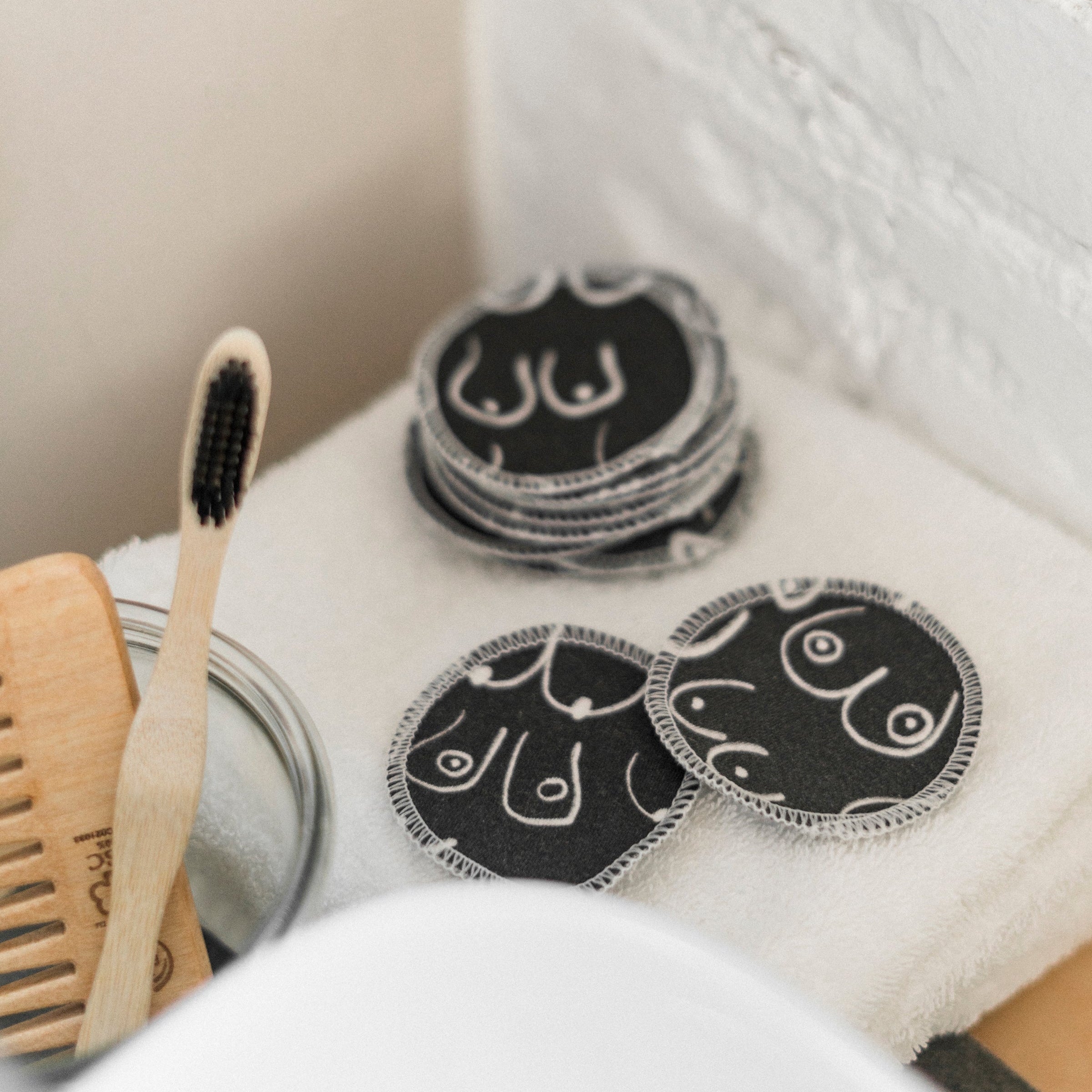 Black and white resuable cotton makeup pads on a white cloth by Freon Collective stacked