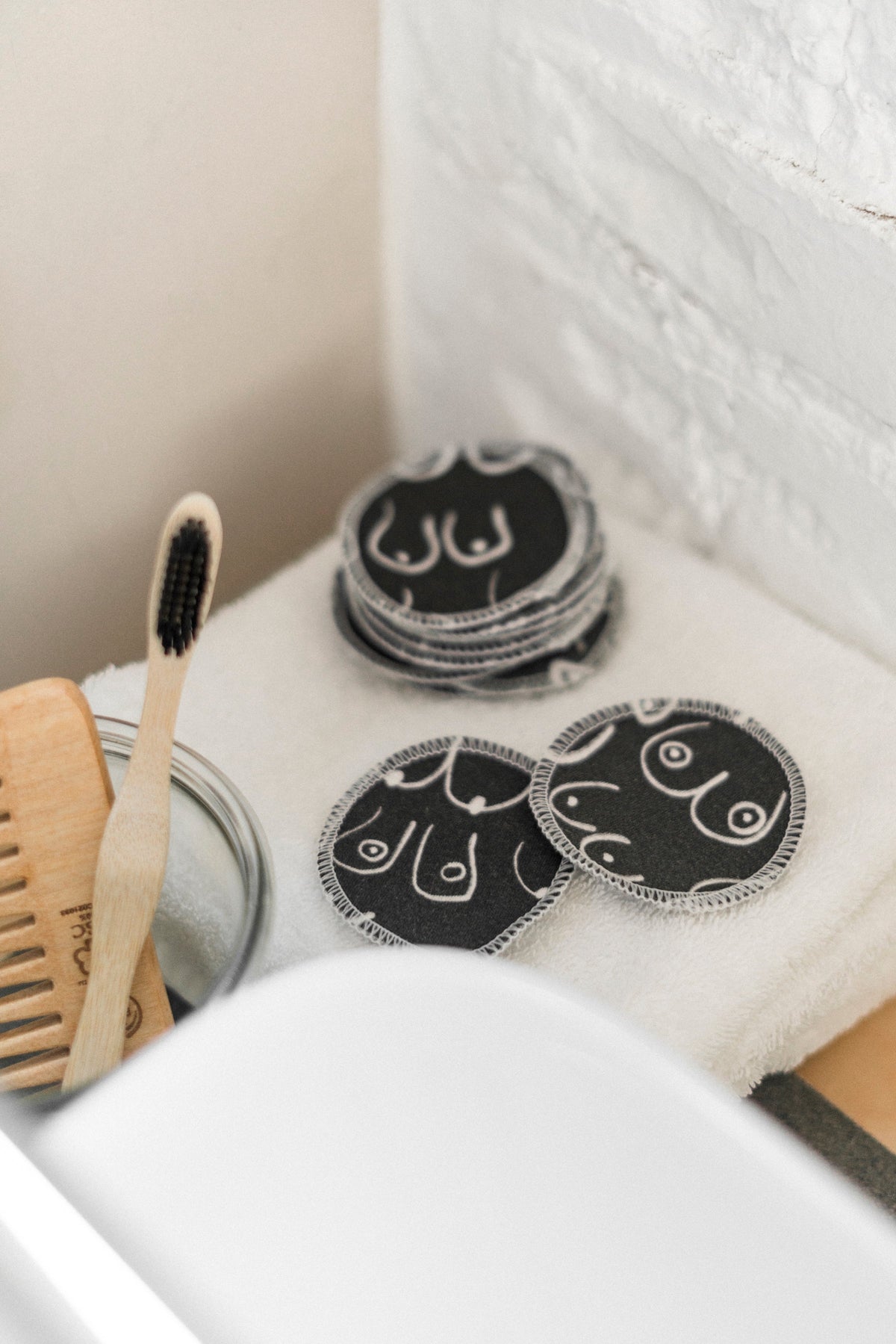 Black and white resuable cotton makeup pads on a white cloth by Freon Collective stacked