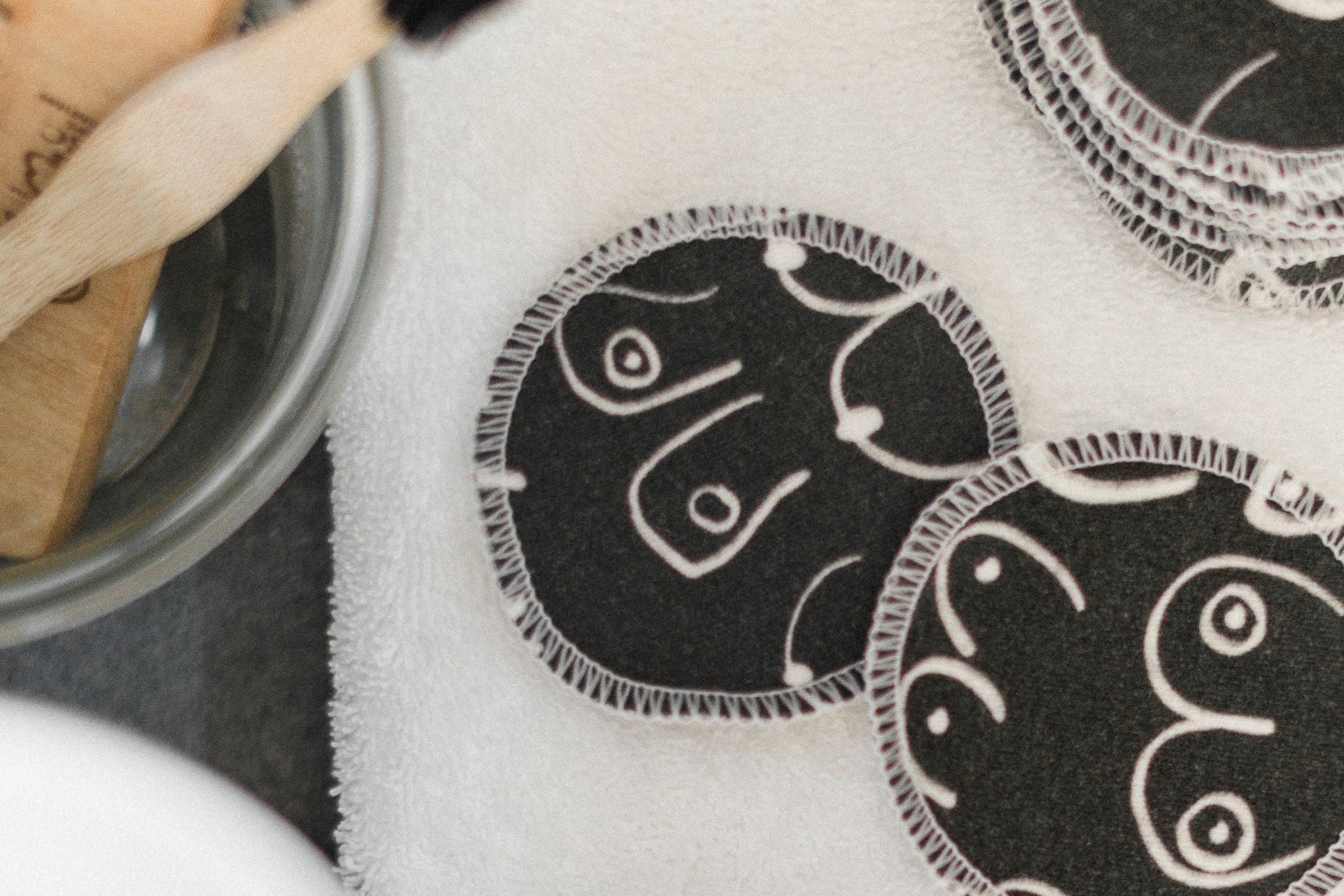 Black and white resuable cotton makeup pads on a white cloth by Freon Collective
