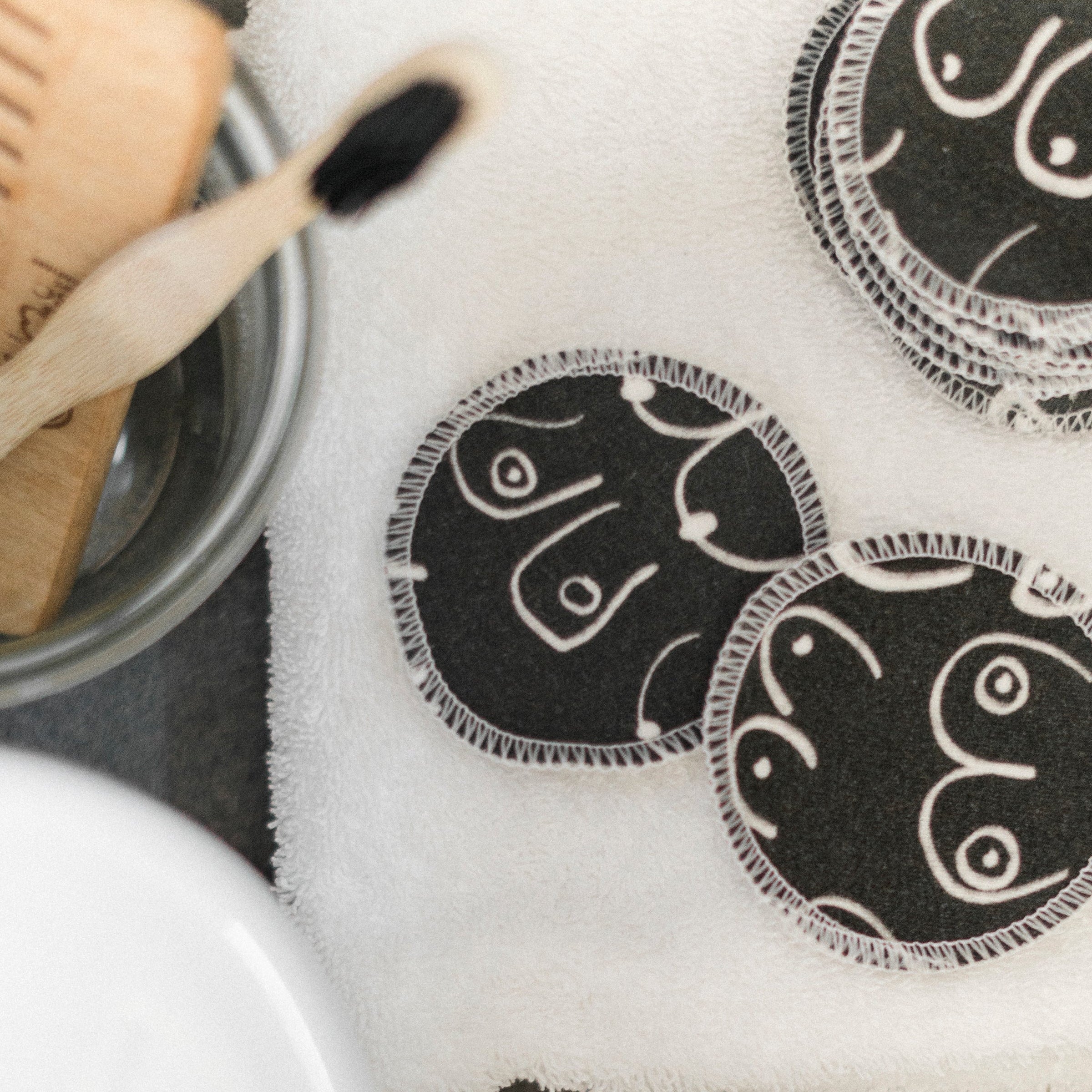 Black and white resuable cotton makeup pads on a white cloth by Freon Collective