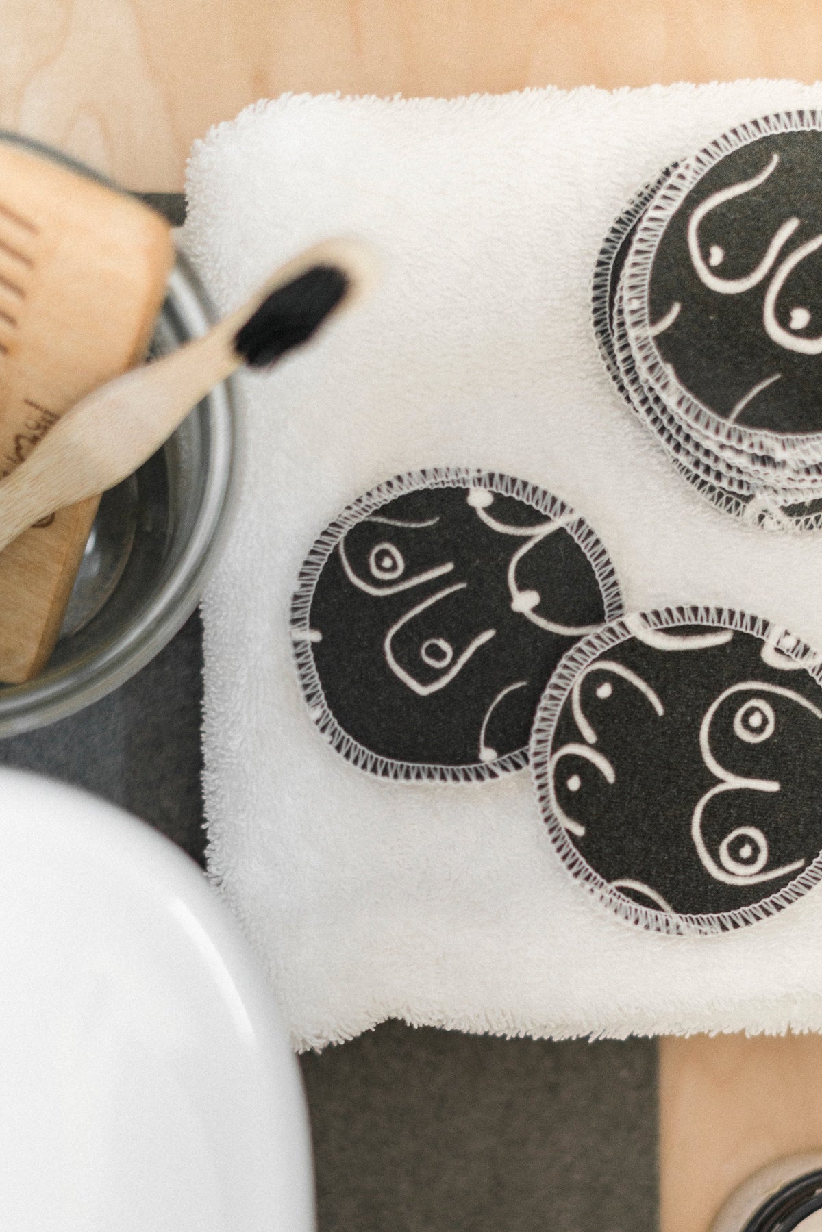Black and white resuable cotton makeup pads on a white cloth by Freon Collective