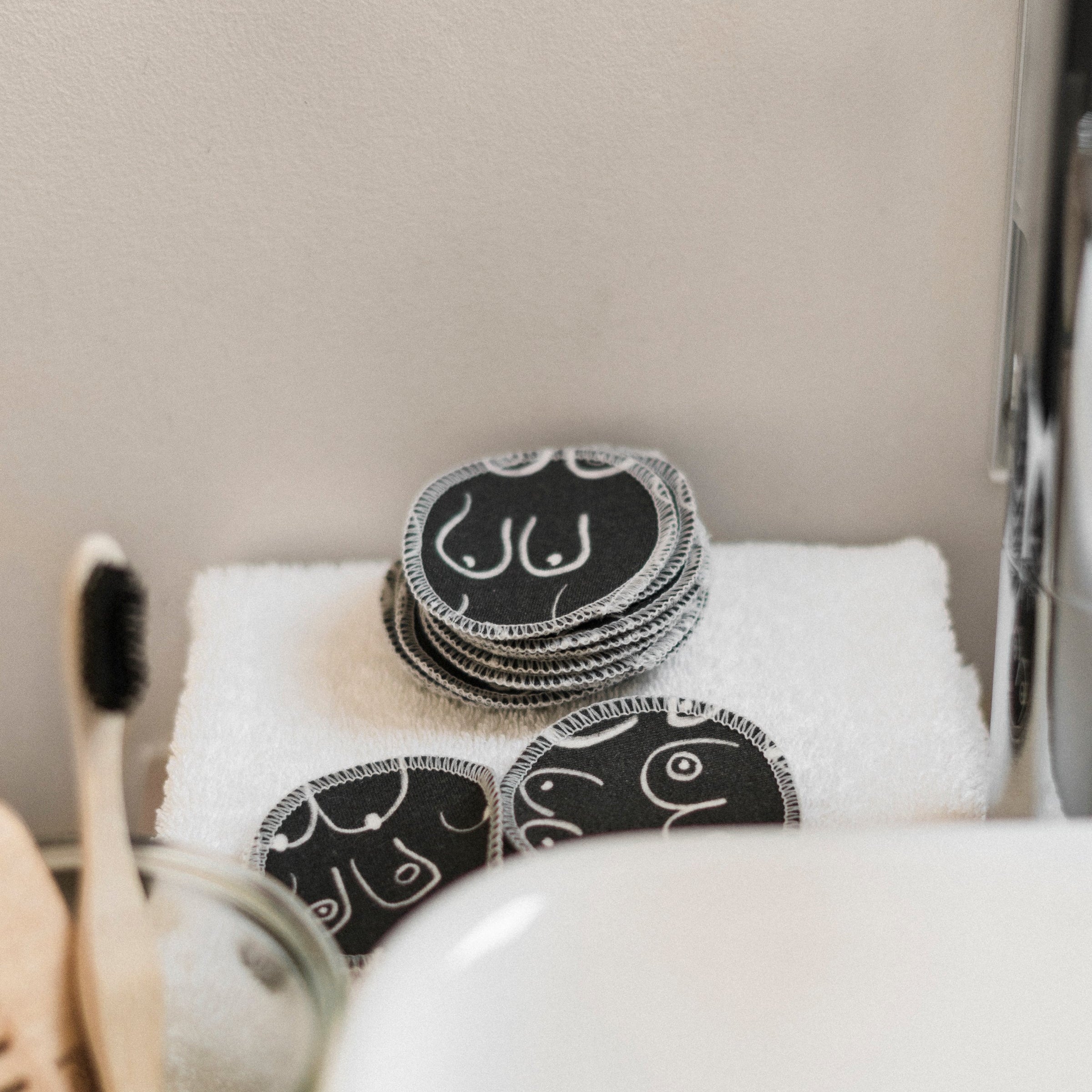 Black and white resuable cotton makeup pads on a white cloth by Freon Collective bathroom corner