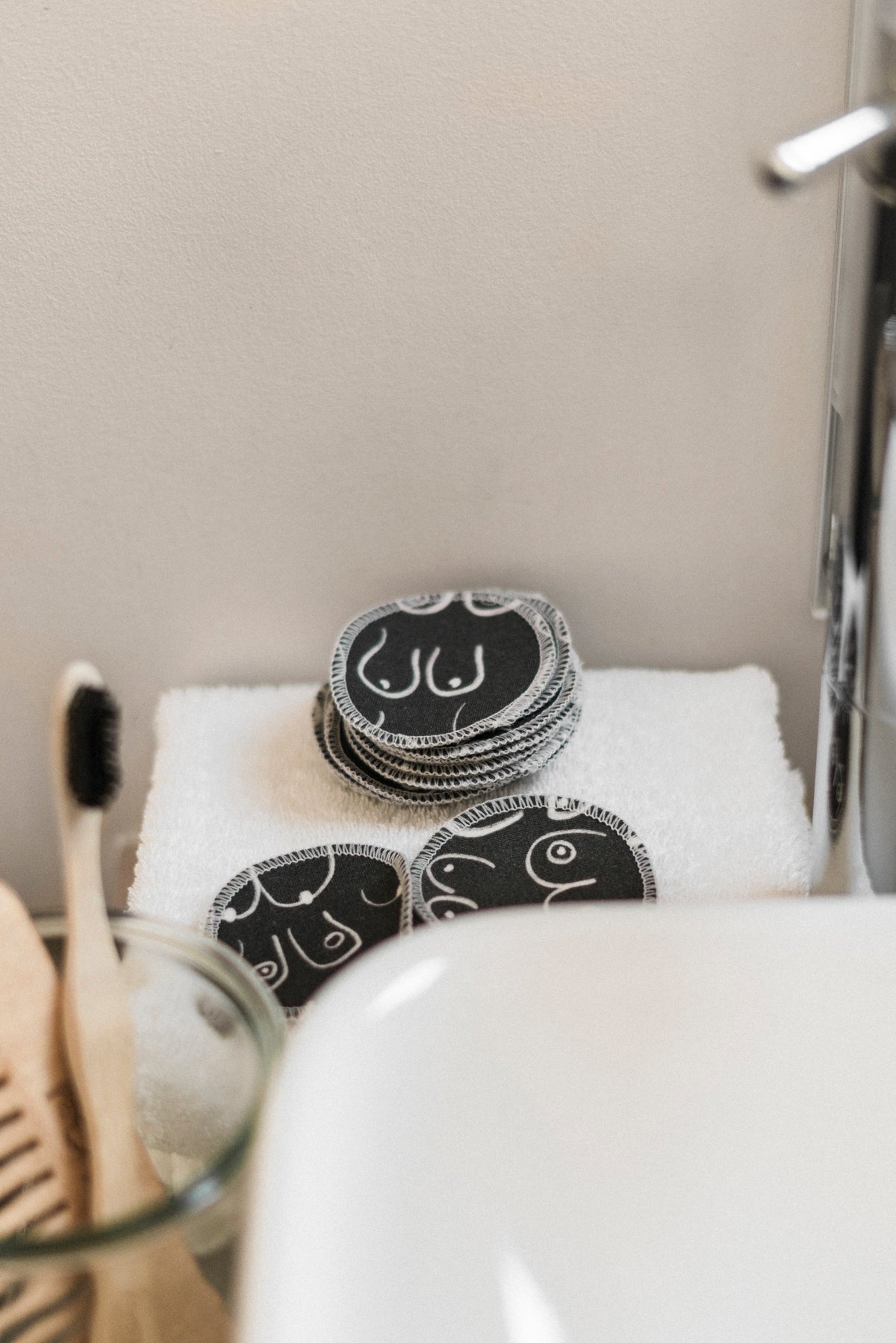 Black and white resuable cotton makeup pads on a white cloth by Freon Collective bathroom corner