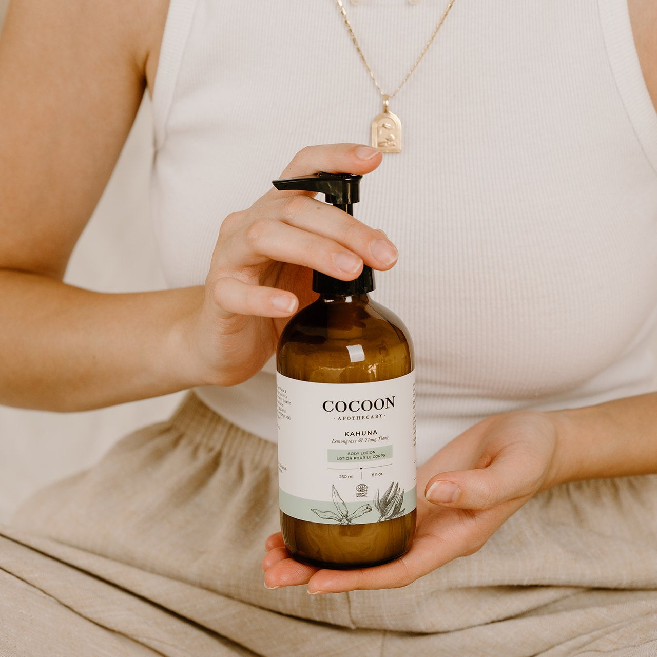 Person holding a bottle of 'Cocoon' product with a neutral background
