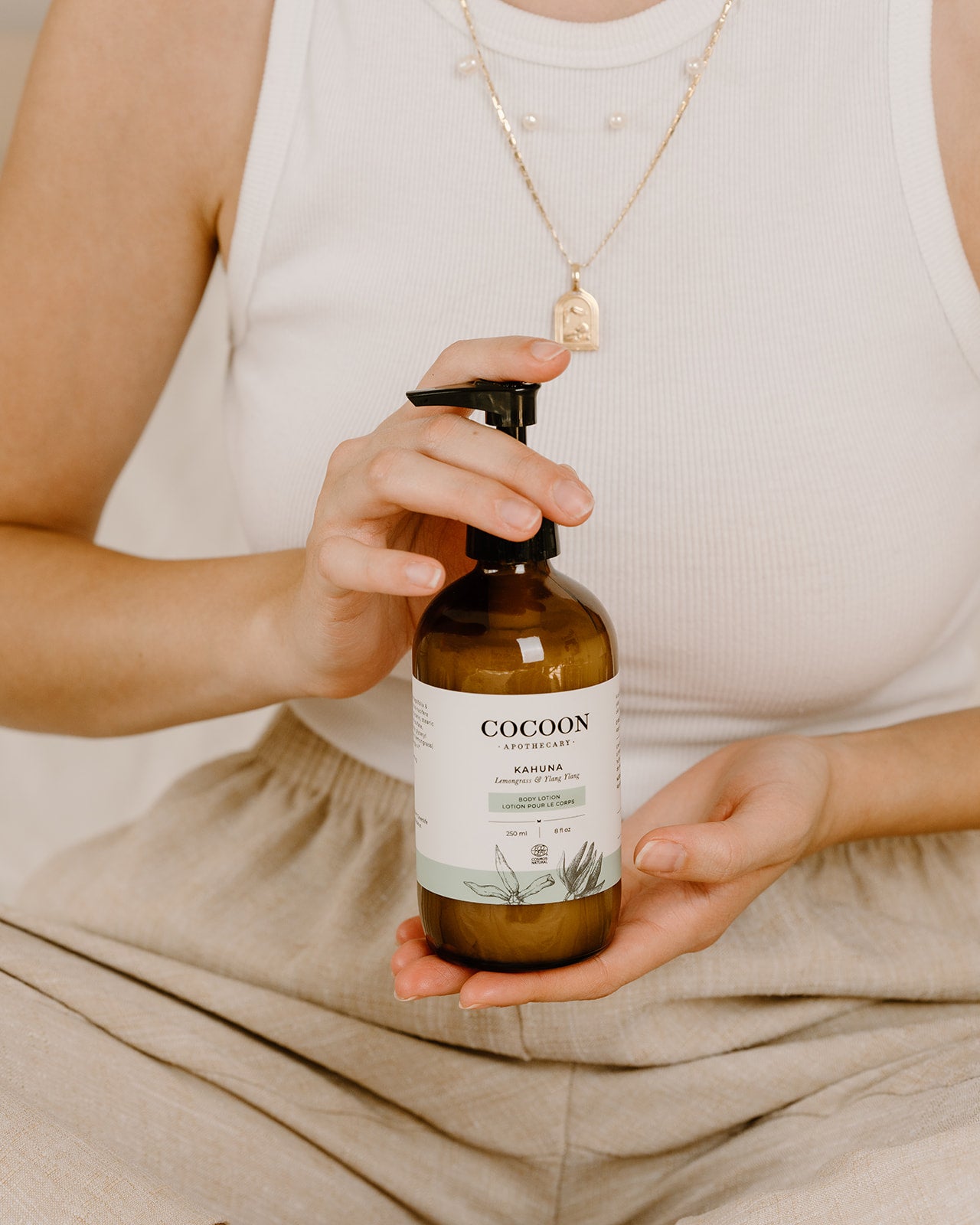Person holding a bottle of 'Cocoon' product with a neutral background