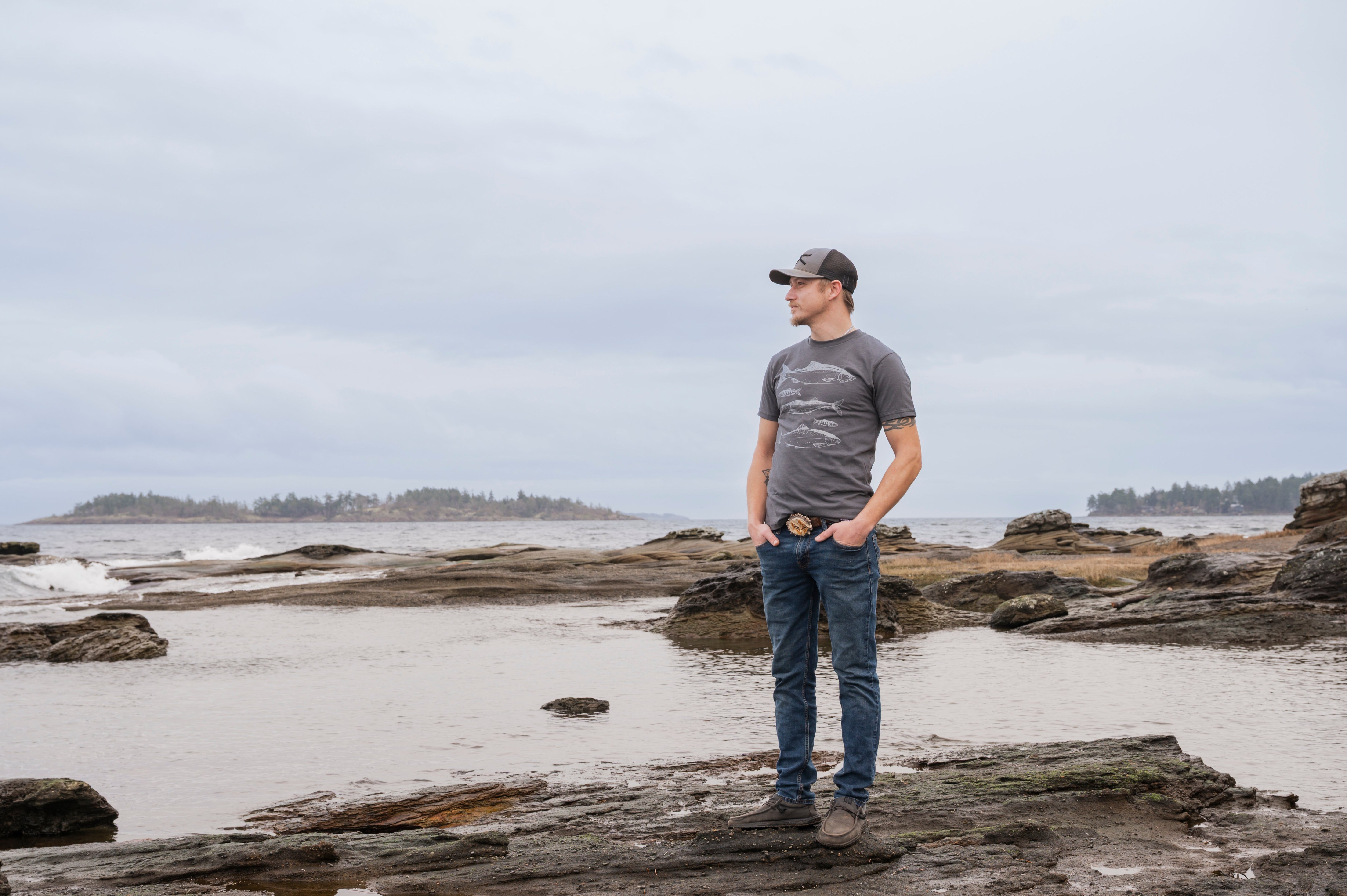 Man standing on a rocky beach with water and sky in the background