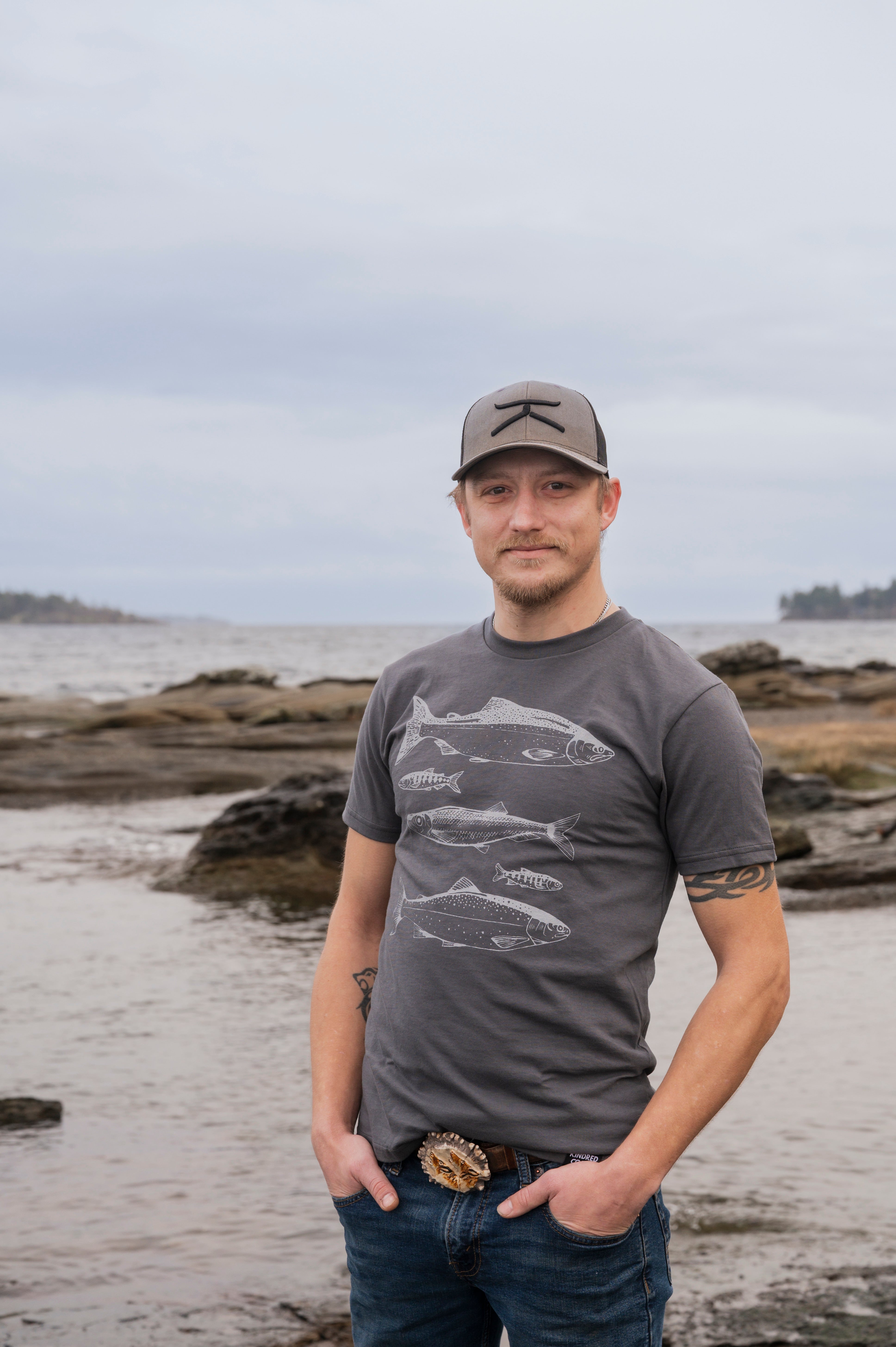 Man wearing a gray t-shirt with fish design on a beach
