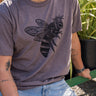 Man wearing a gray t-shirt with a bee design outdoors