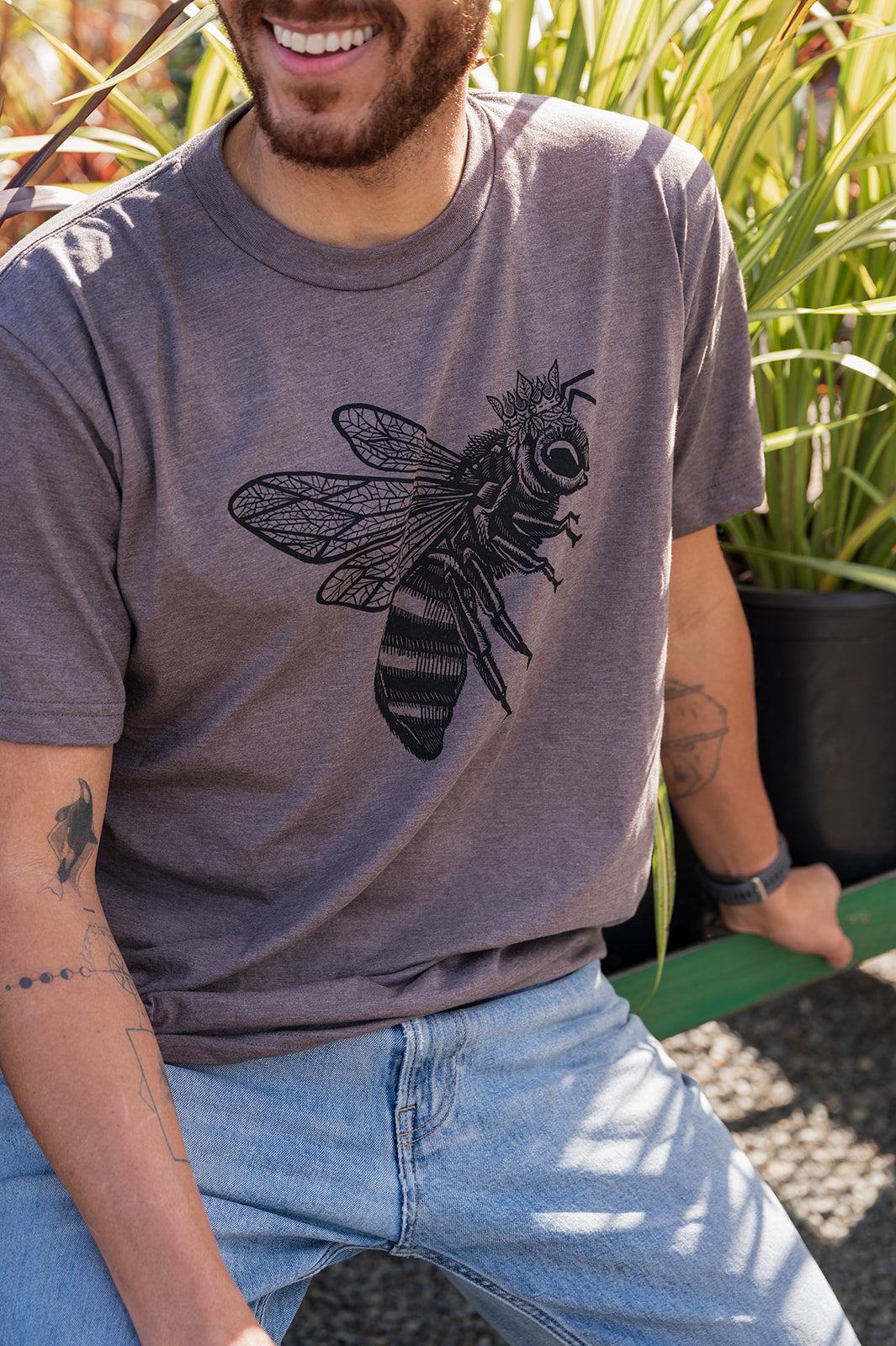 Man wearing a gray t-shirt with a bee design outdoors