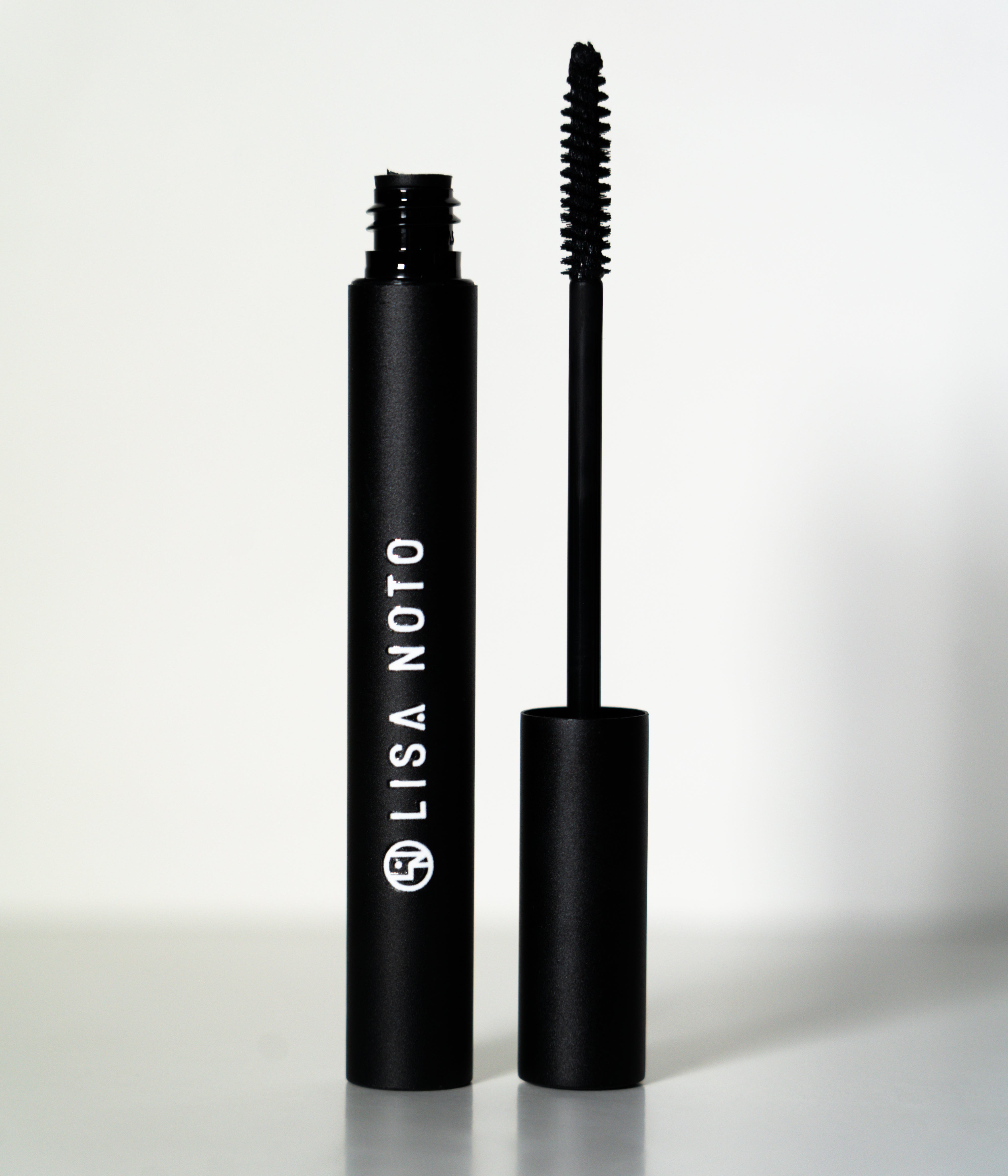 LISA NOTO Volumizing Natural Mascarain a matte black tube, shown with the wand removed and standing beside the cap on a clean white background.