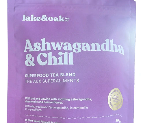 Ashwagandha + Chill herbal tea blend pouch beside a glass of brewed tea and fresh flowers.