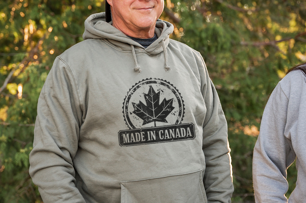 Man wearing a 'Made in Canada' hoodie standing outdoors with trees in the background