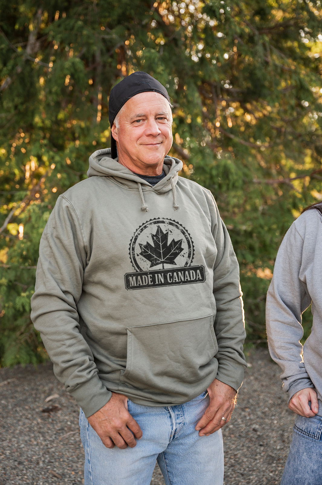 Man wearing a 'Made in Canada' hoodie standing outdoors with trees in the background