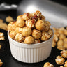 Bowl of candied maple bacon popcorn on a wooden surface from Toronto Popcorn company