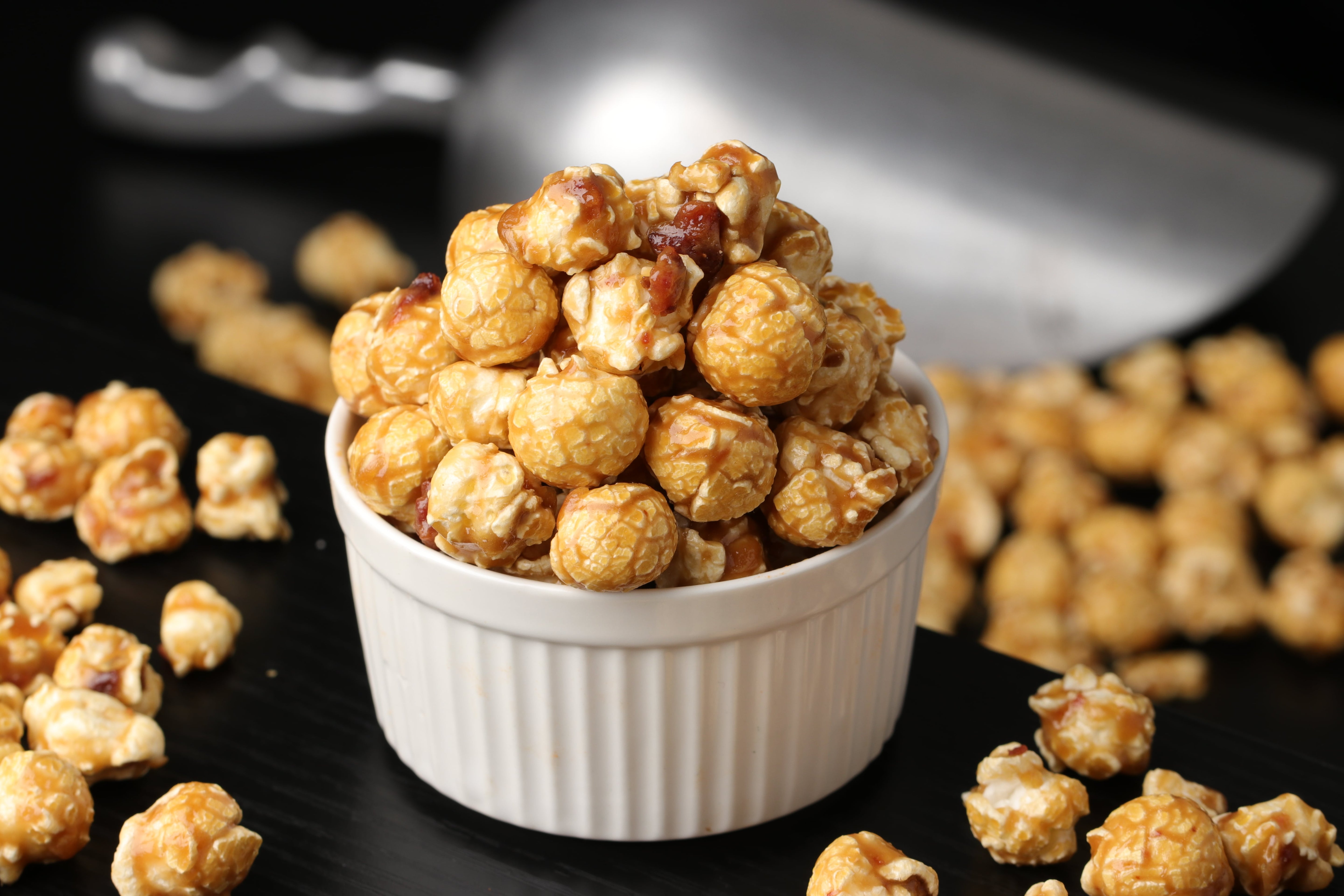 Bowl of candied maple bacon popcorn on a wooden surface from Toronto Popcorn company