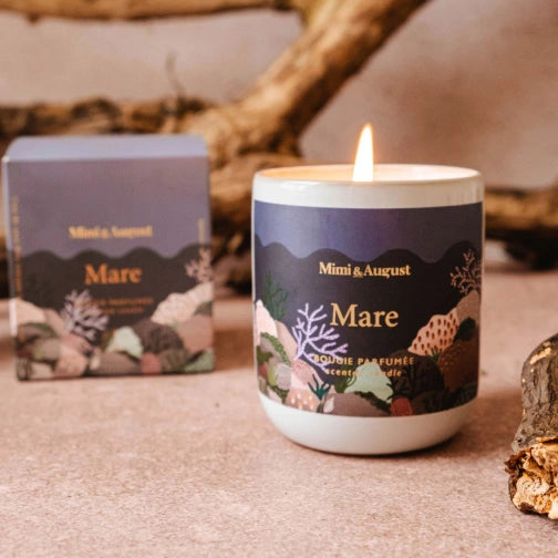 Candle with 'Mimi & August' label on a textured surface