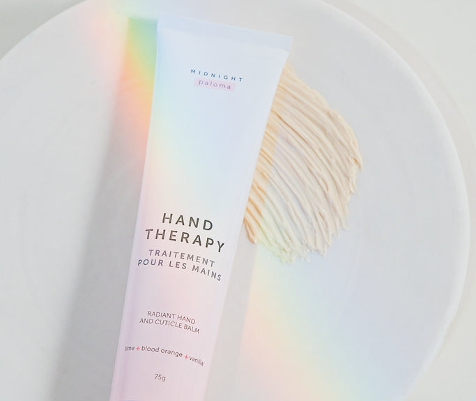 Hand Therapy Cream in a tube on a plate, featuring Blood Orange, Lime, Vanilla, and Grapefruit scents.