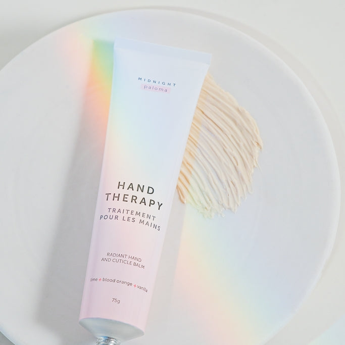 Hand Therapy Cream in a tube on a plate, featuring Blood Orange, Lime, Vanilla, and Grapefruit scents.